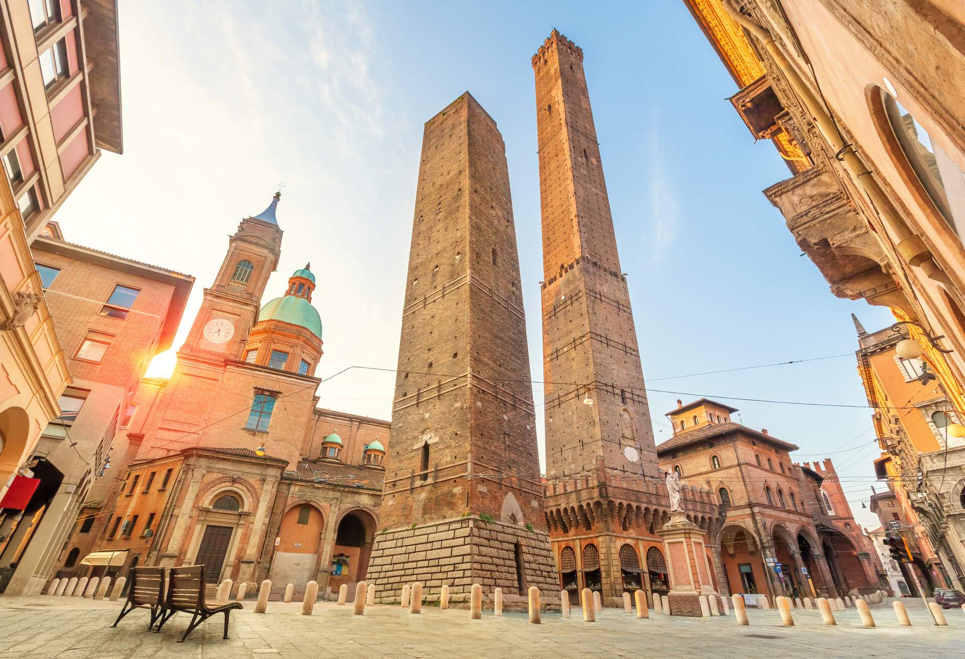 The iconic leaning towers of Asinelli and Garisenda stand tall in the small square, surrounded by historic buildings, as if frozen in time during their gradual descent.