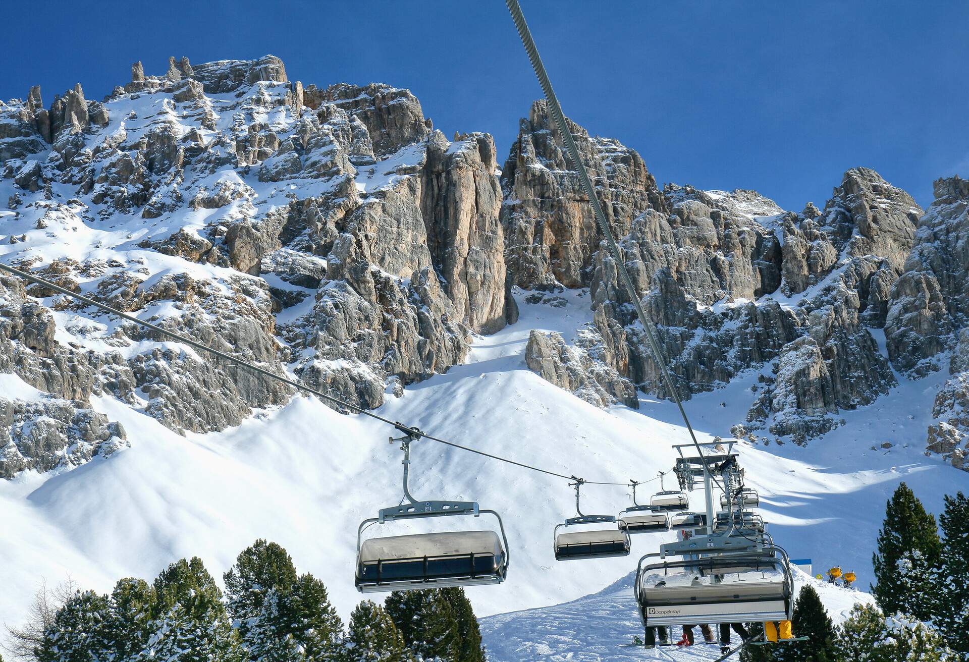 Skiing on the dolomites, Cabs for skiers above the horizon in the background mountains. Val di Fiemme, Italy.