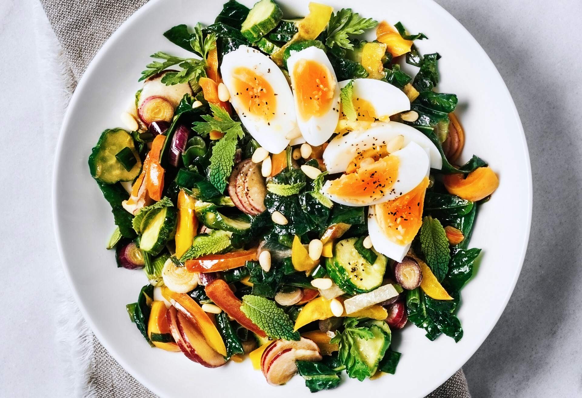 A bowl of fresh salad with boiled eggs on white background