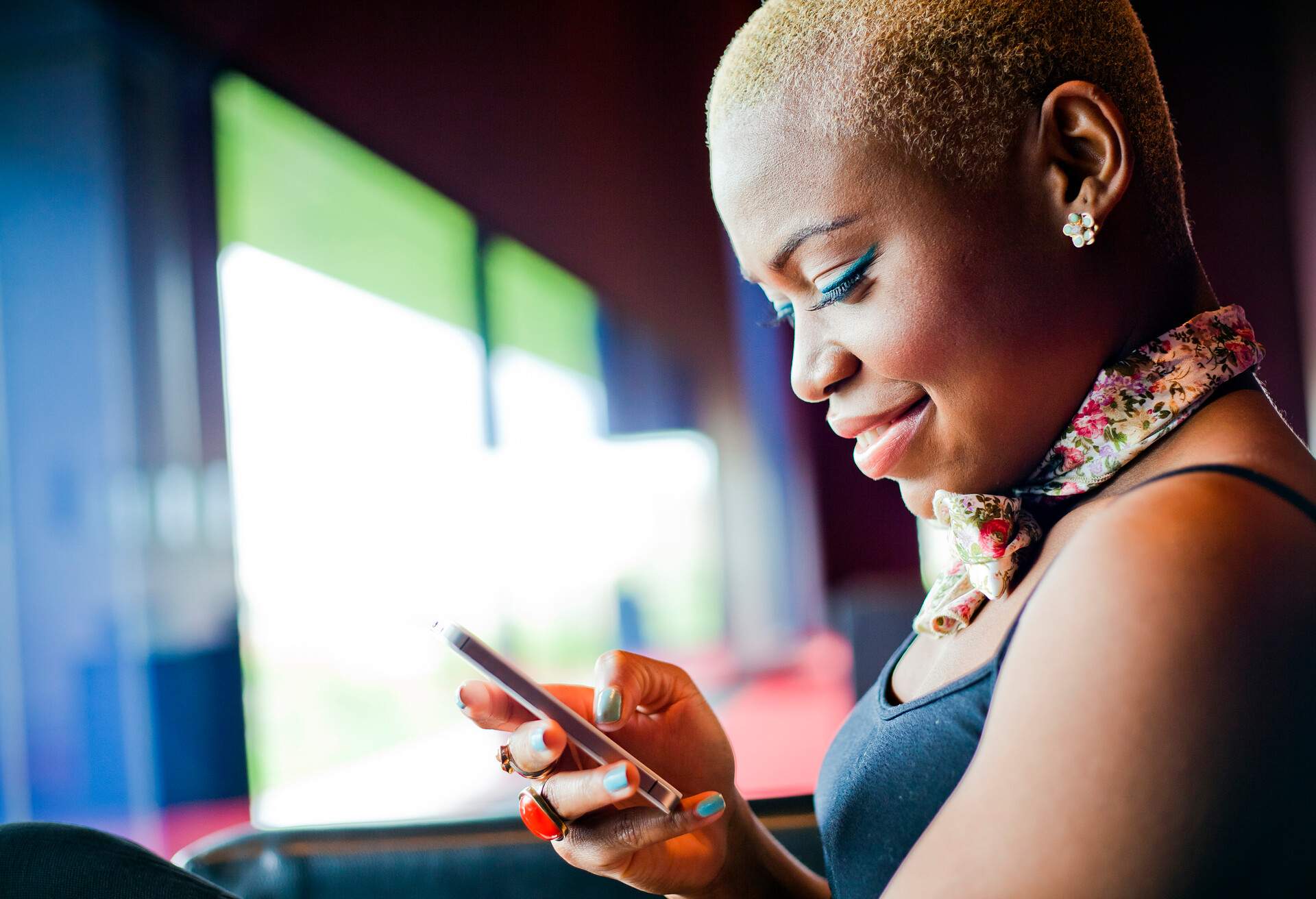 A well dressed young female using a cellular device inside a building.