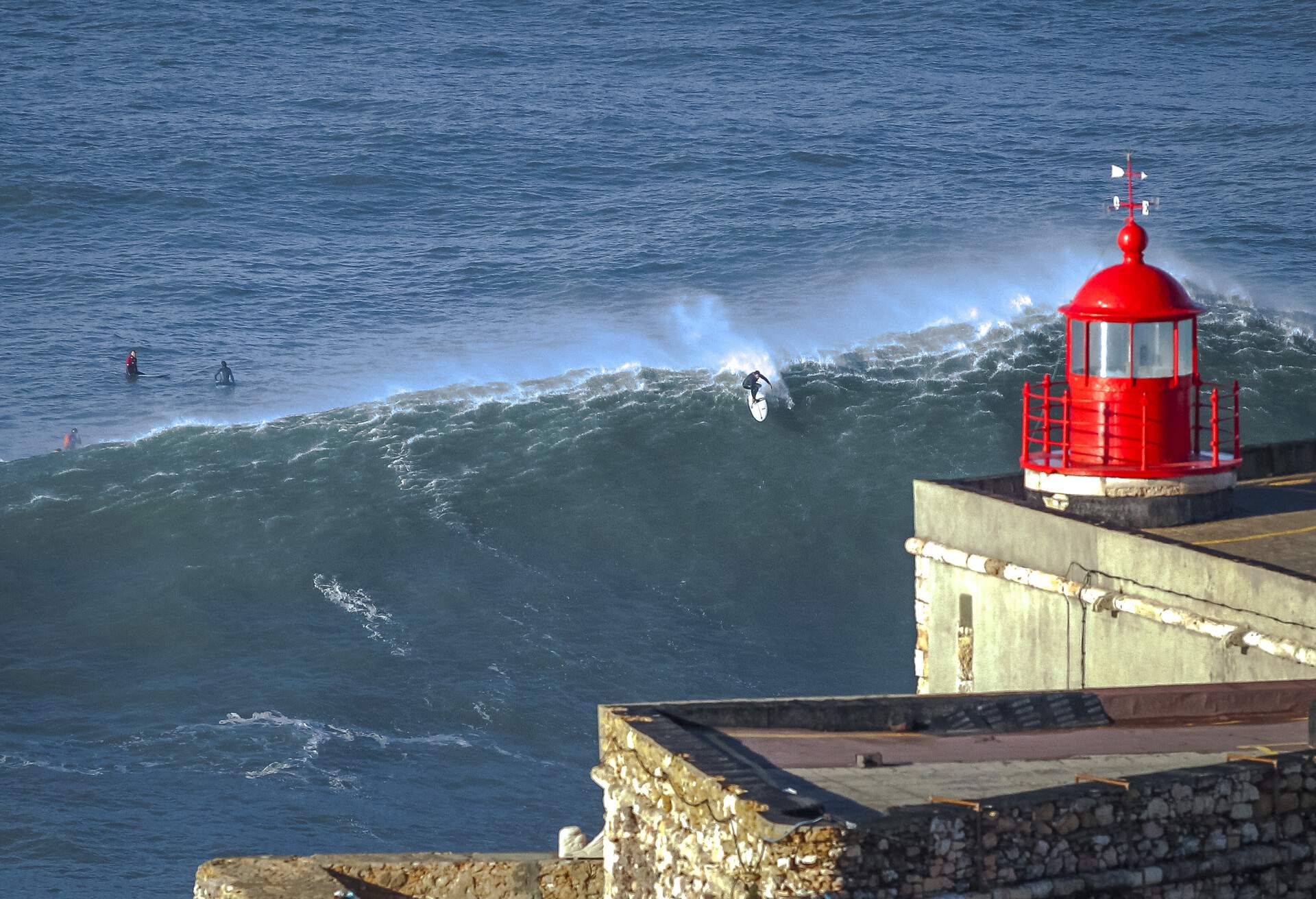 Surfers practice the sport near the lighthouse of Nazaré, Portugal,