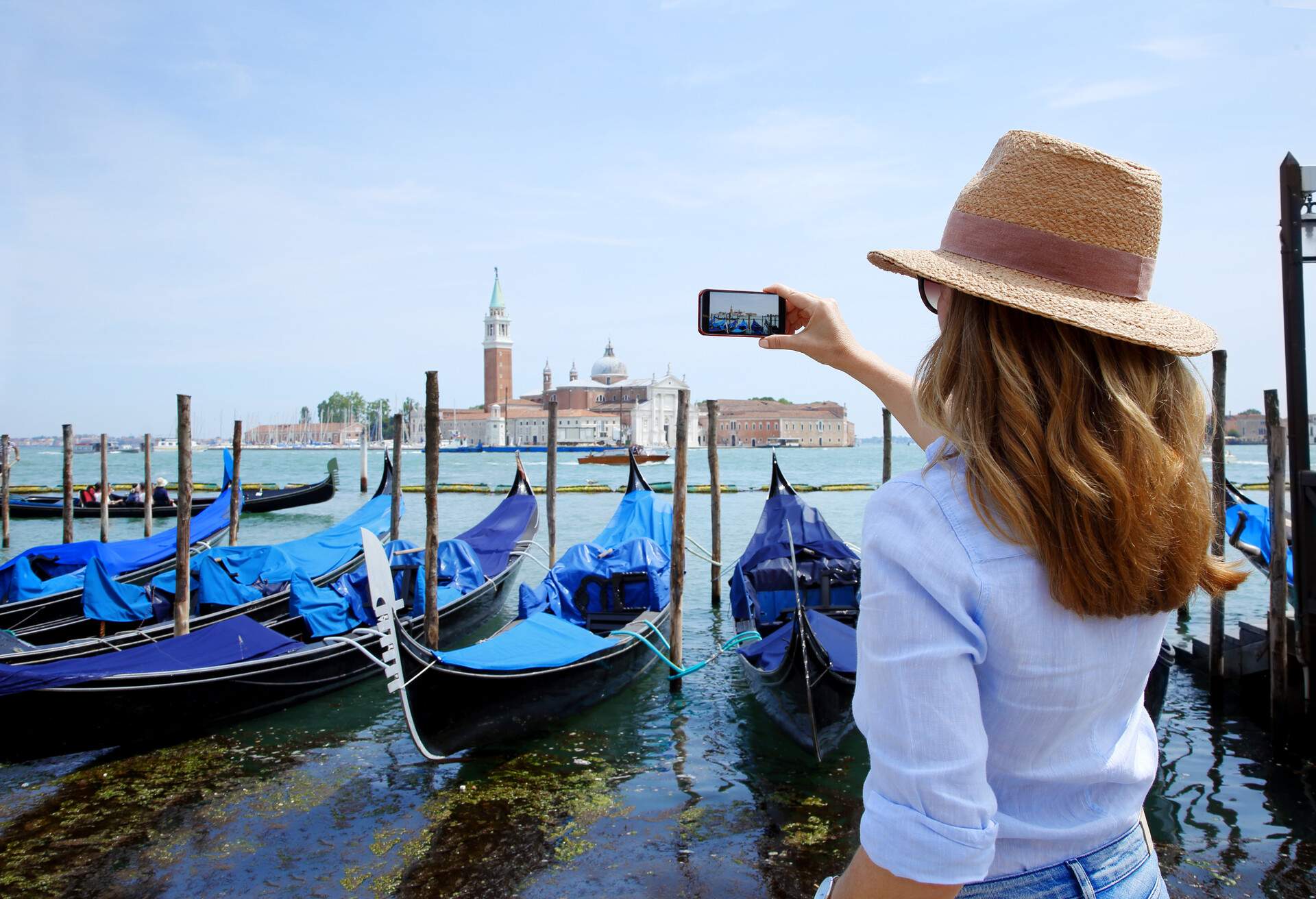 Rear view shot of a female tourist with mobile phone capturing the moments while on Venice at canal.; Shutterstock ID 497230141