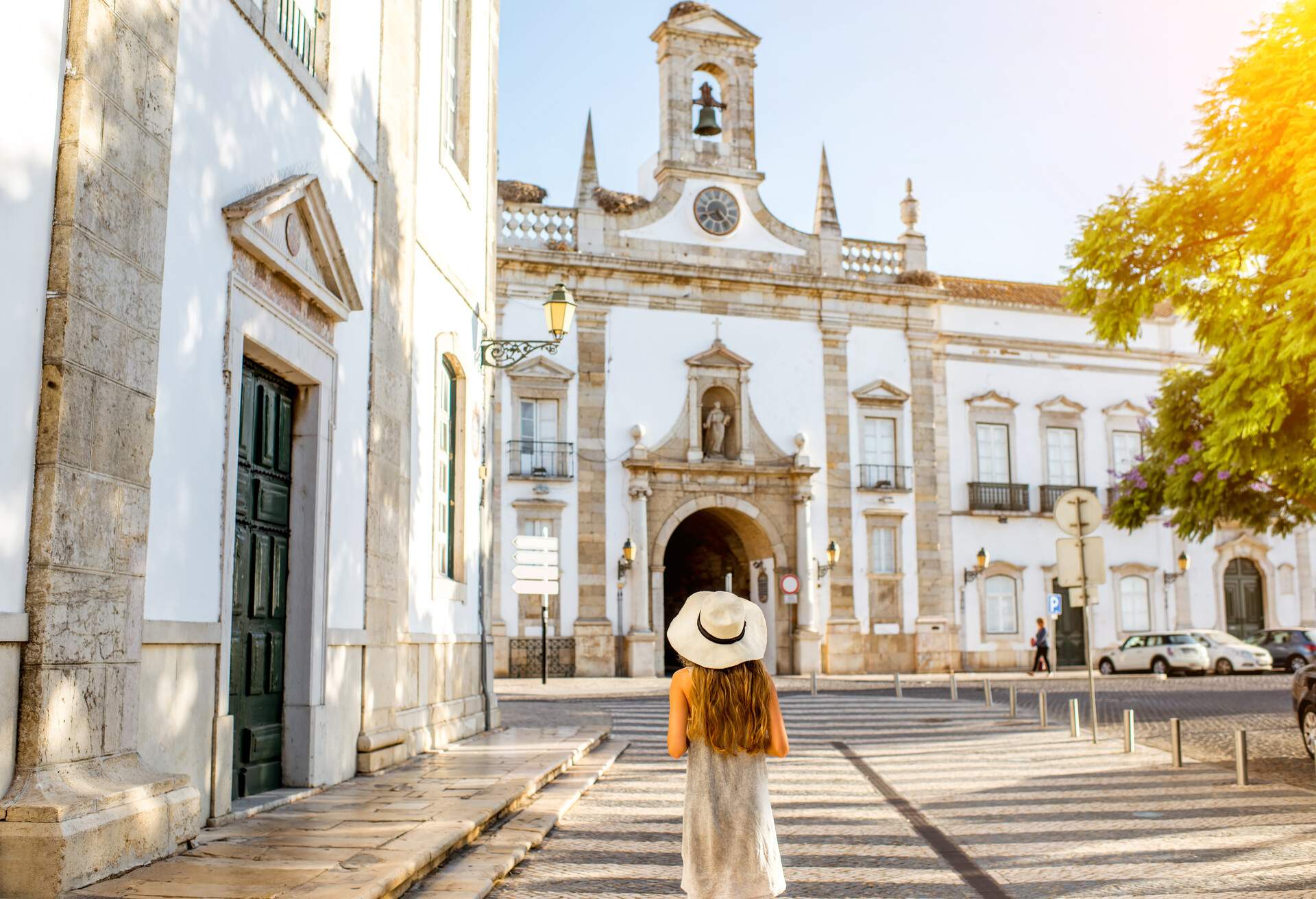 Young woman tourist standing on the city gate background in Faro town on the south of Portugal