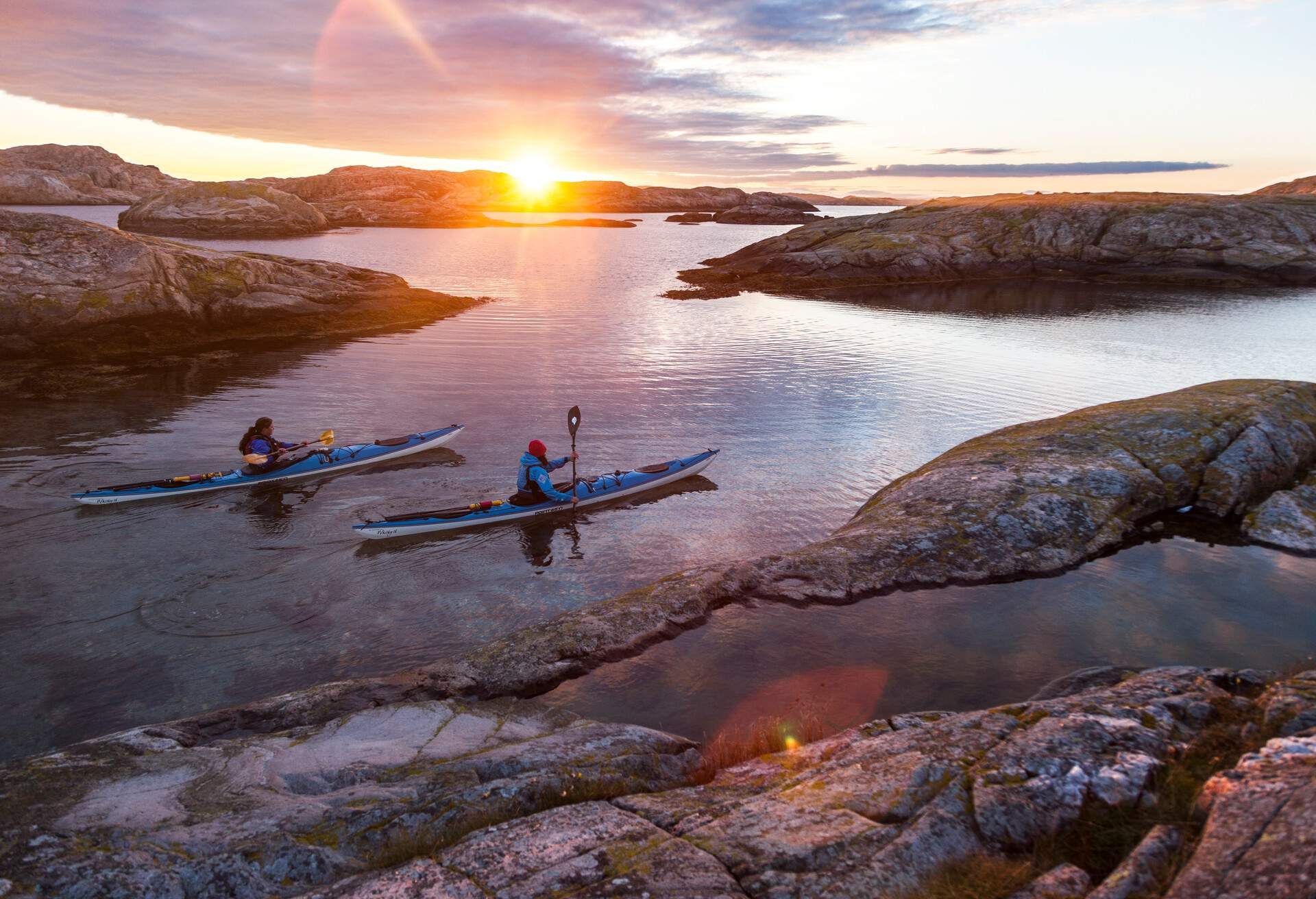 two people in kayaks during sunset in the swedish archipelago