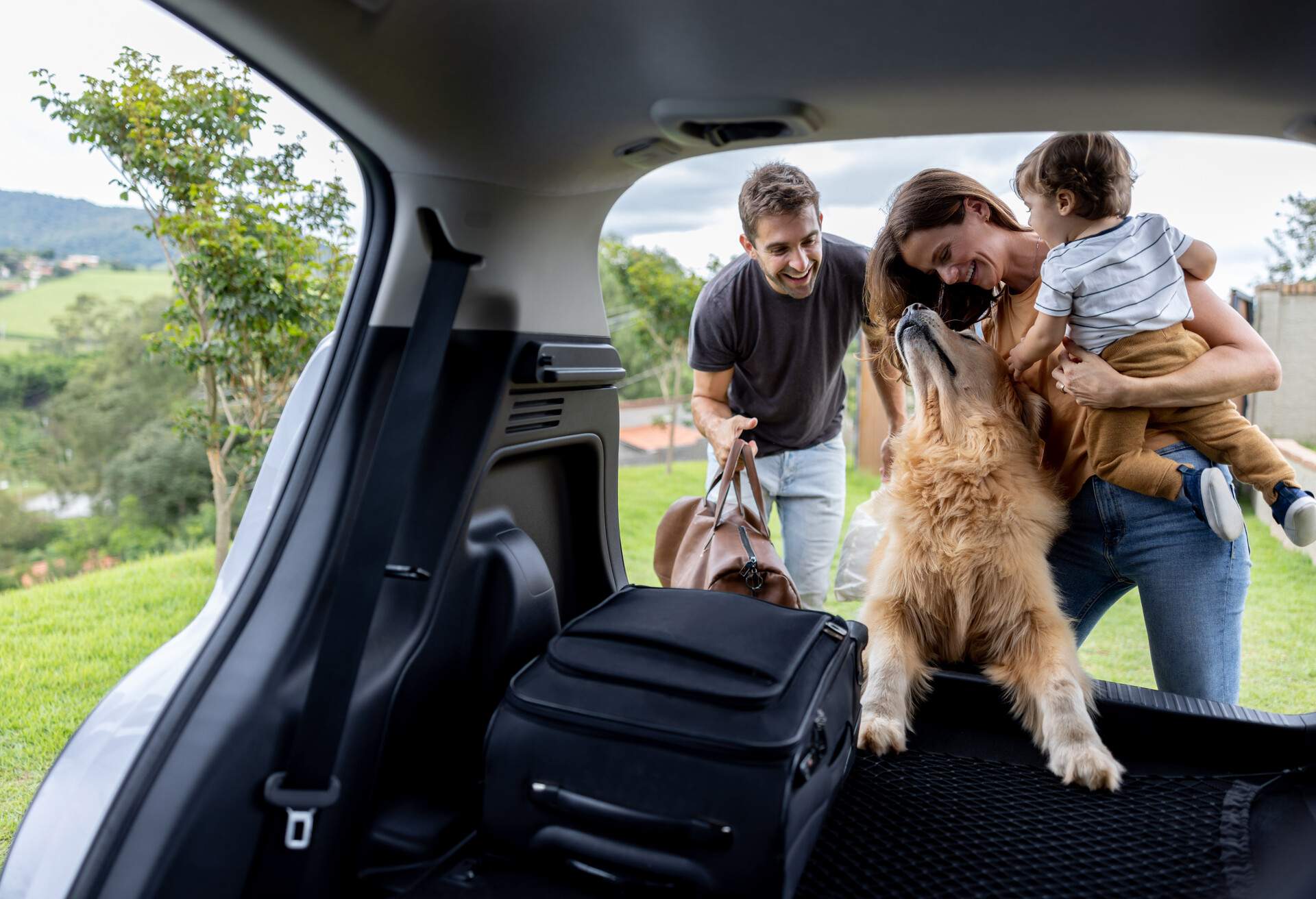 Happy Brazilian family loading bags in the car and going on a road trip - travel concepts