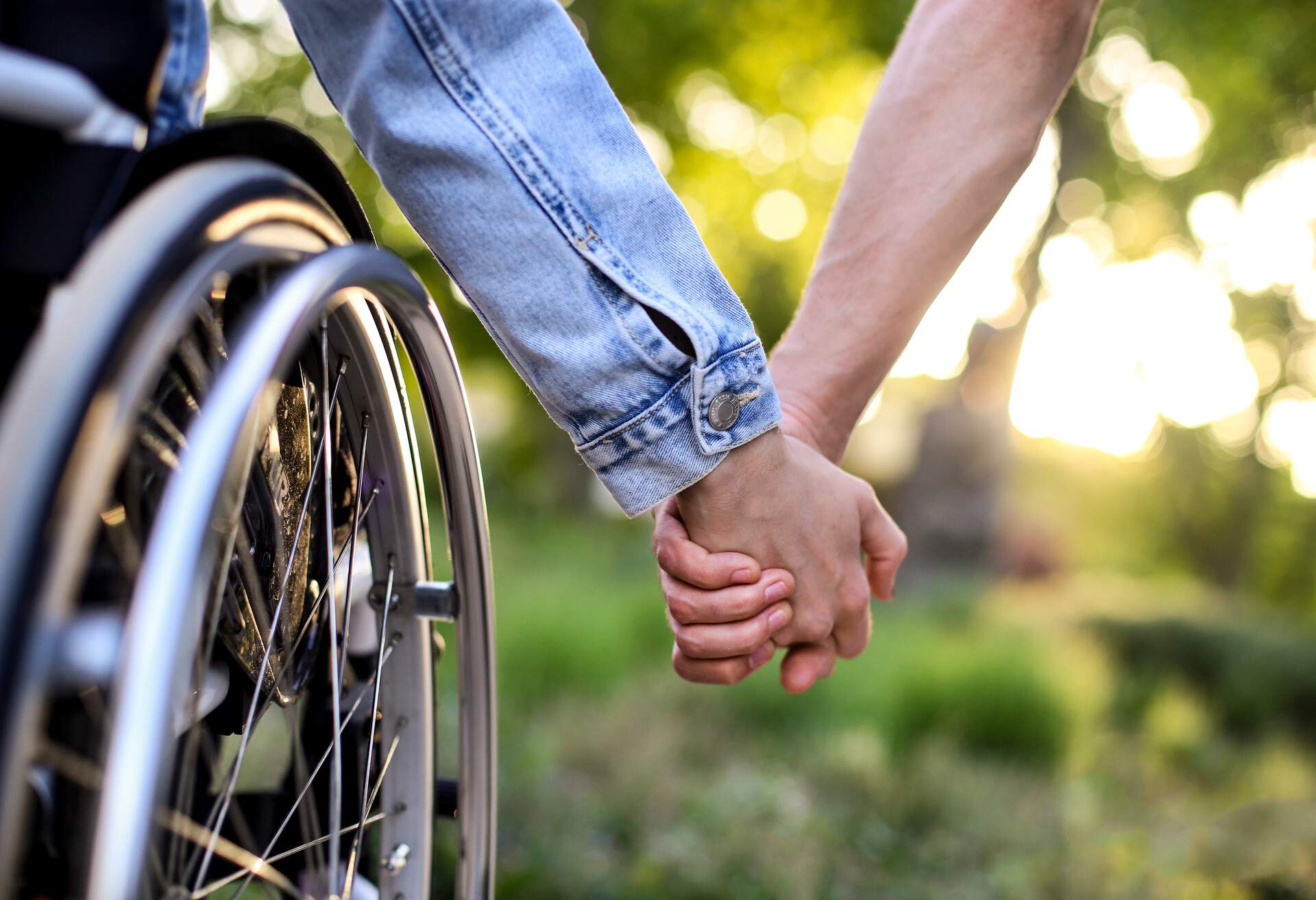 Disabled young woman and her boyfriend holding hands. Unrecognizable Caucasian people.