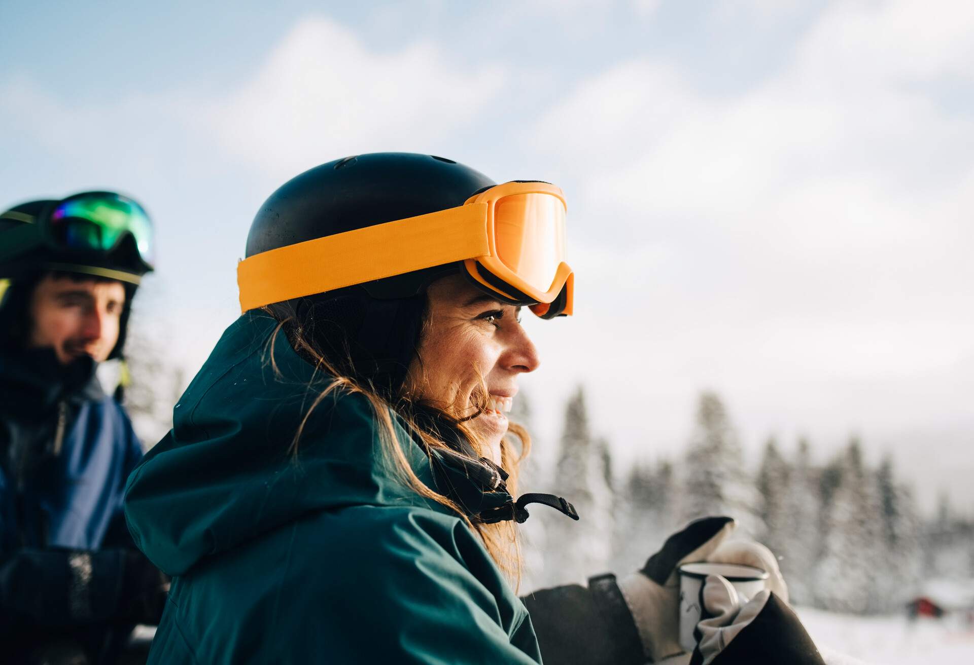 A smiling woman in winter clothes and yellow ski goggles.