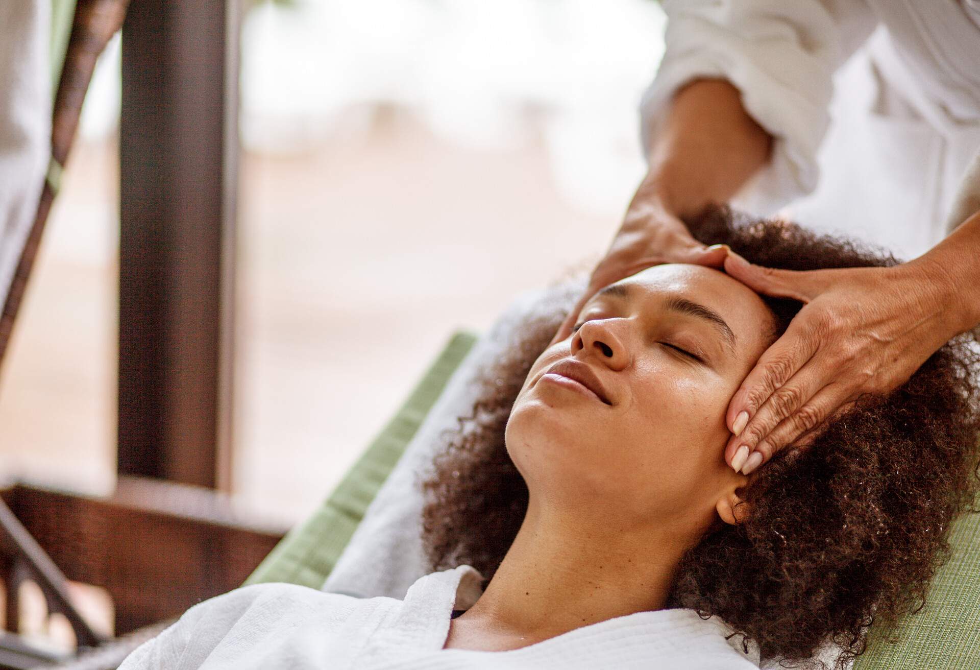 Young mixed race woman enjoying a relaxing head massage at the luxury wellness resort.