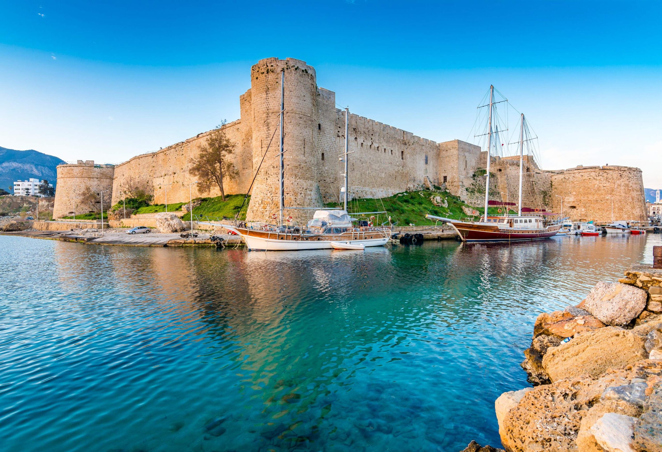 An old fortress with bastions extending from each corner towards the sea, which is teeming with moored boats.