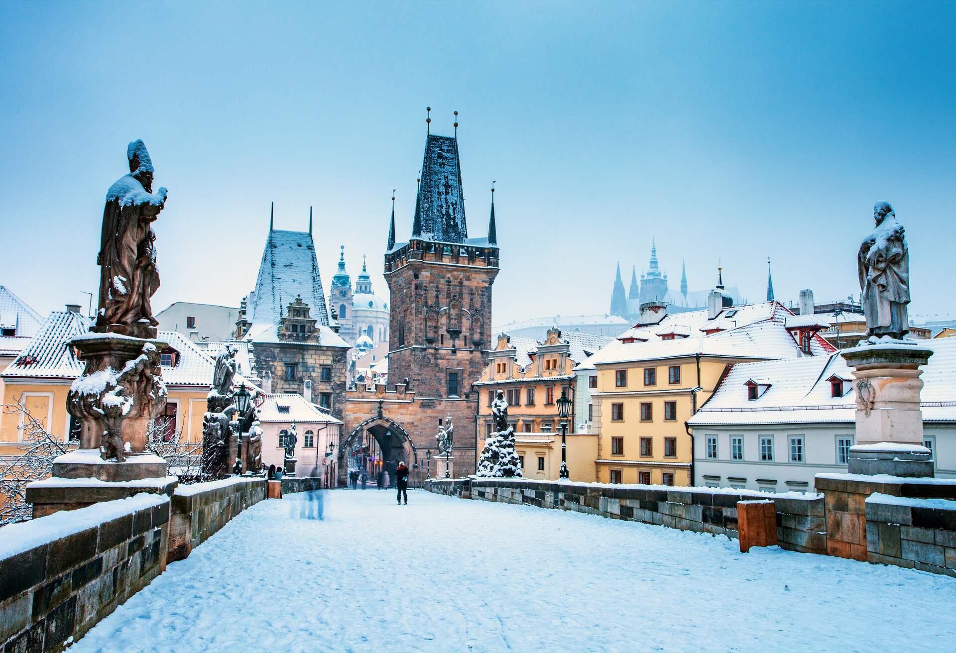 An early morning on the Charles Bridge during a snowstorm, Prague Castle is seen in background.