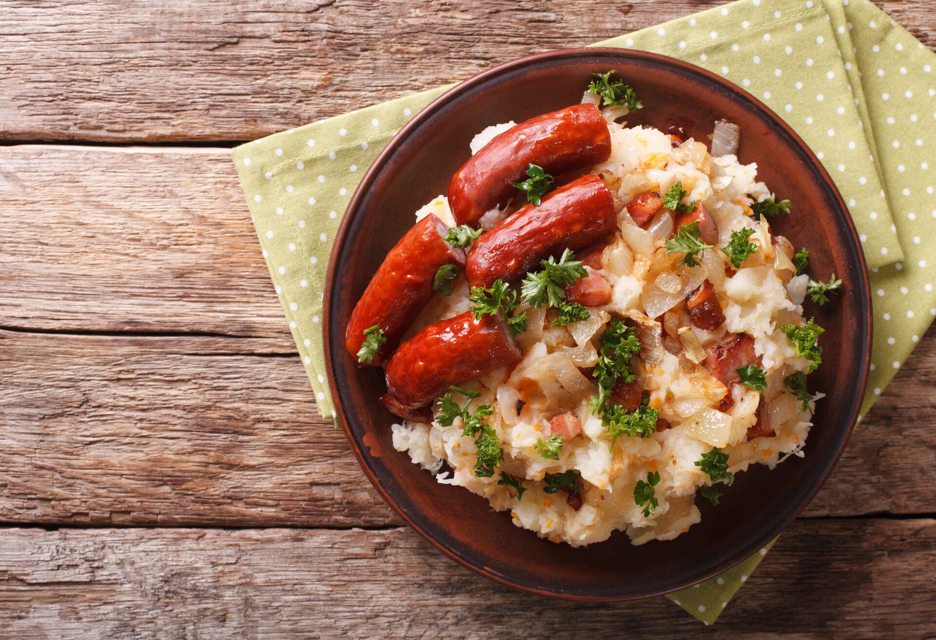 Dutch winter meal: stamppot of potatoes, cabbage and carrots, with sausages close-up on a plate. horizontal view from above