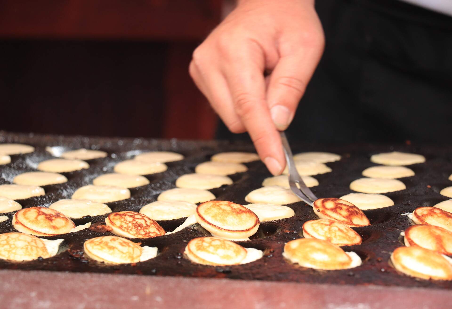 Poffertjes, Dutch small, fluffy pancakes, made on hot cast iron plate, served with powdered sugar and butter.