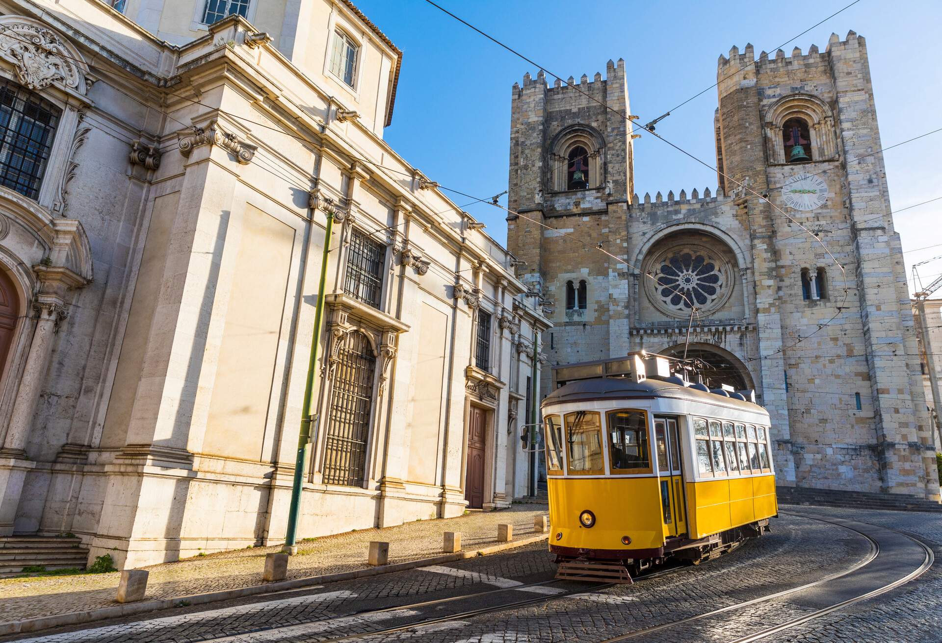 A tram making a turn on a curving tramline, with a stone church in the background.