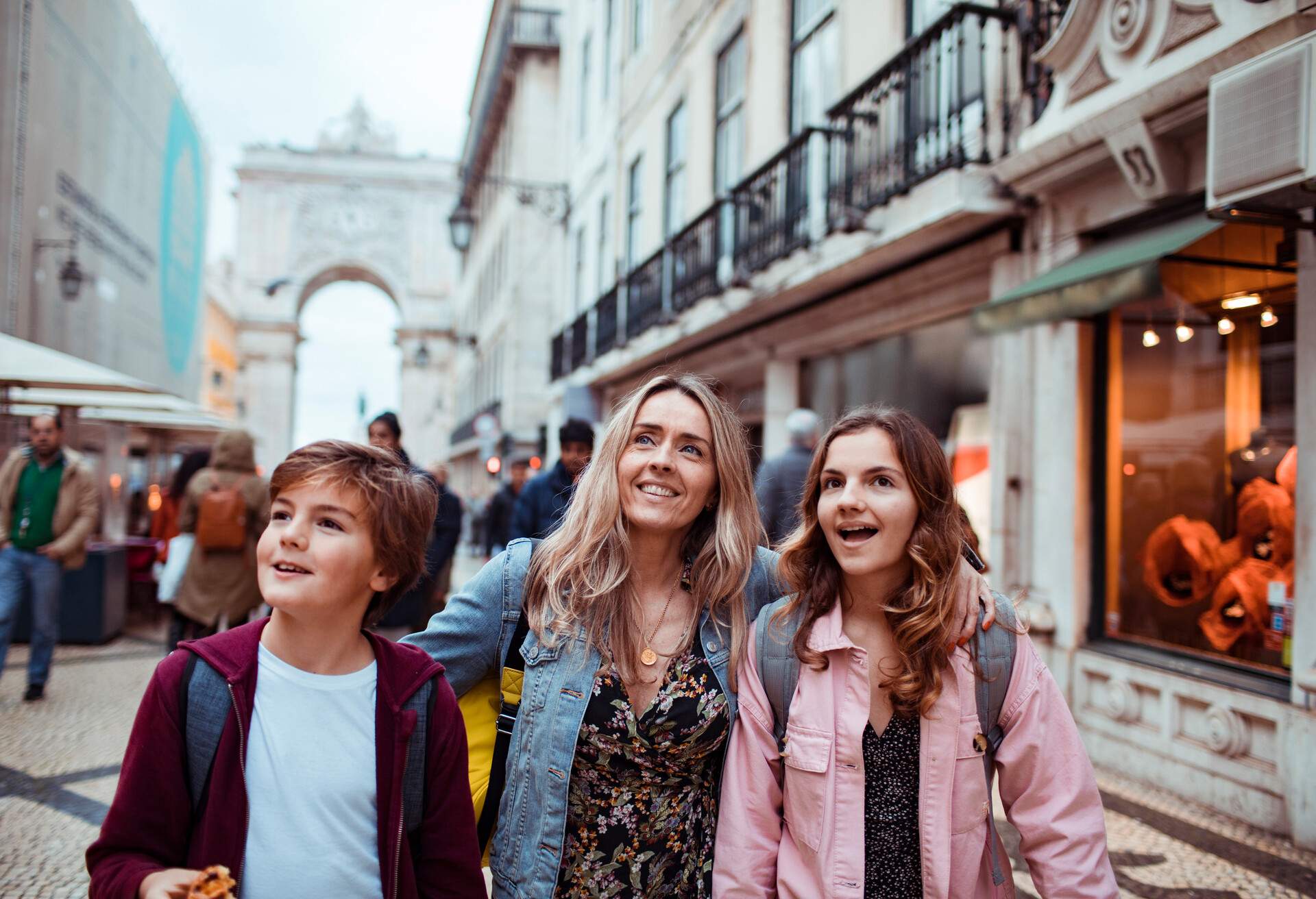 A happy family of a mother with her daughter and son in their casual wear on a busy street.