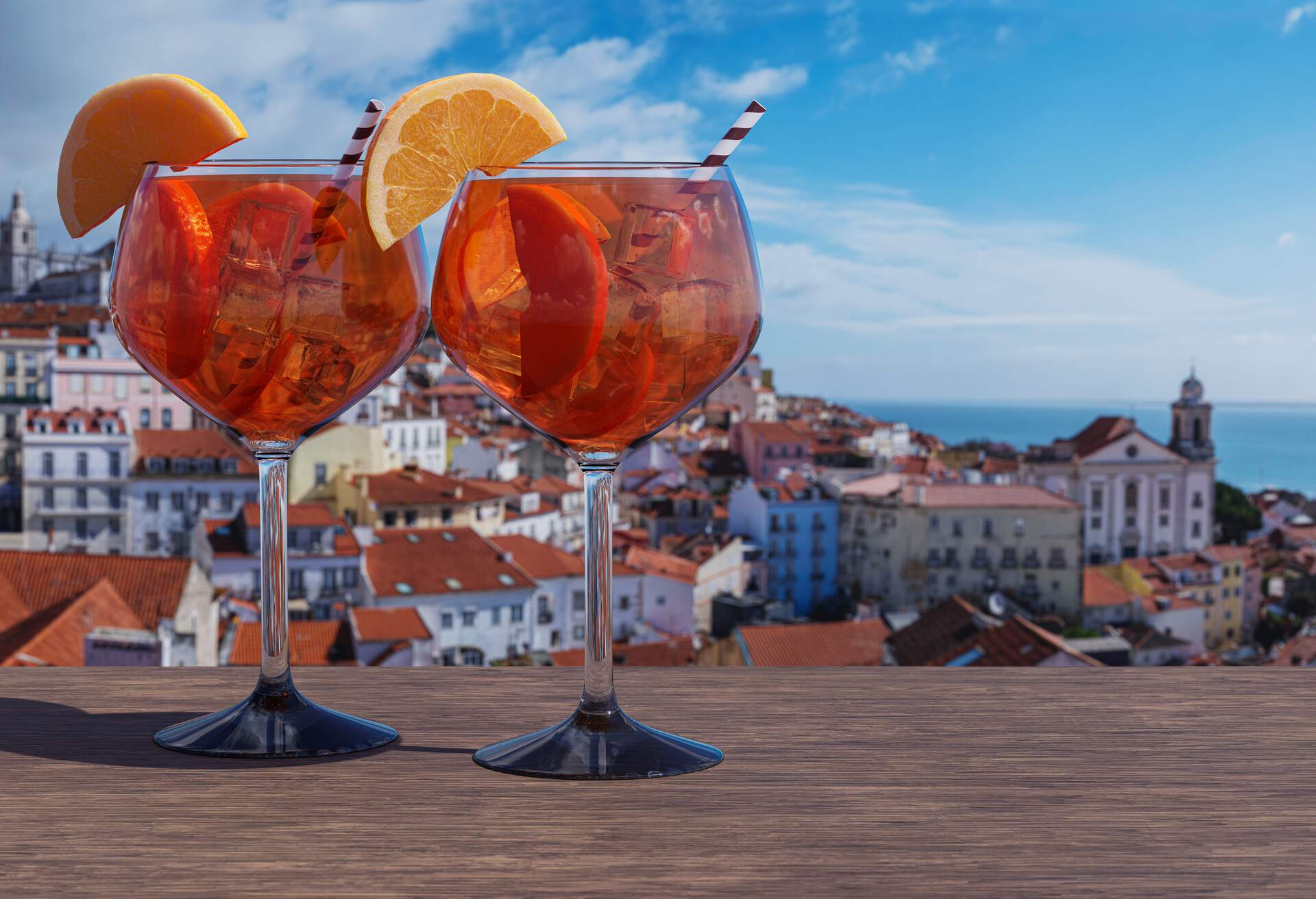 Two glasses of Spritz cocktail with view of Lisbon old town in Alfama district in Lisbon, Portugal.