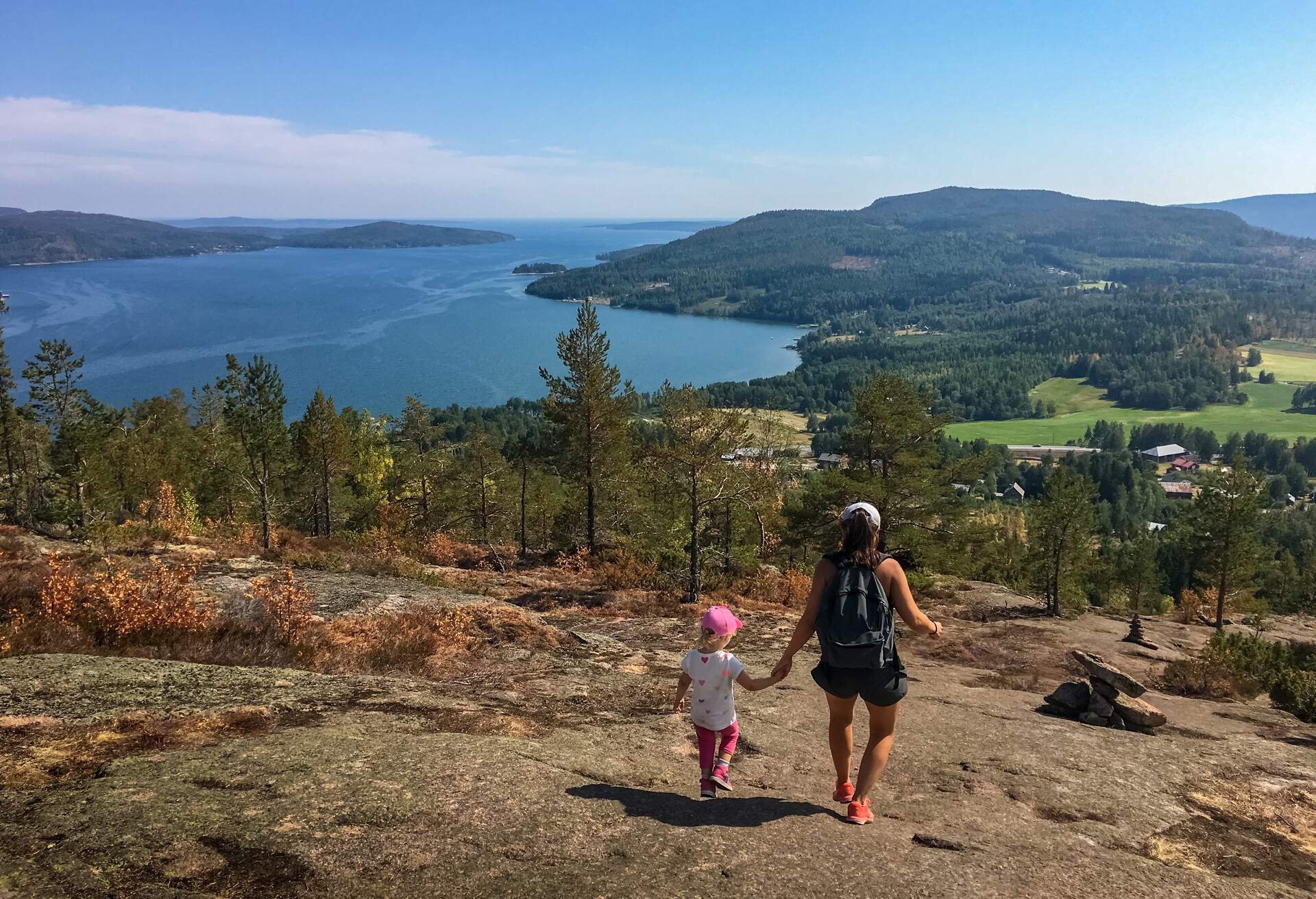 Mother and daughter hiking downhill a mountain. Beautiful view of mountains, sea and forest. Skule mountain, high coast in northern Sweden.