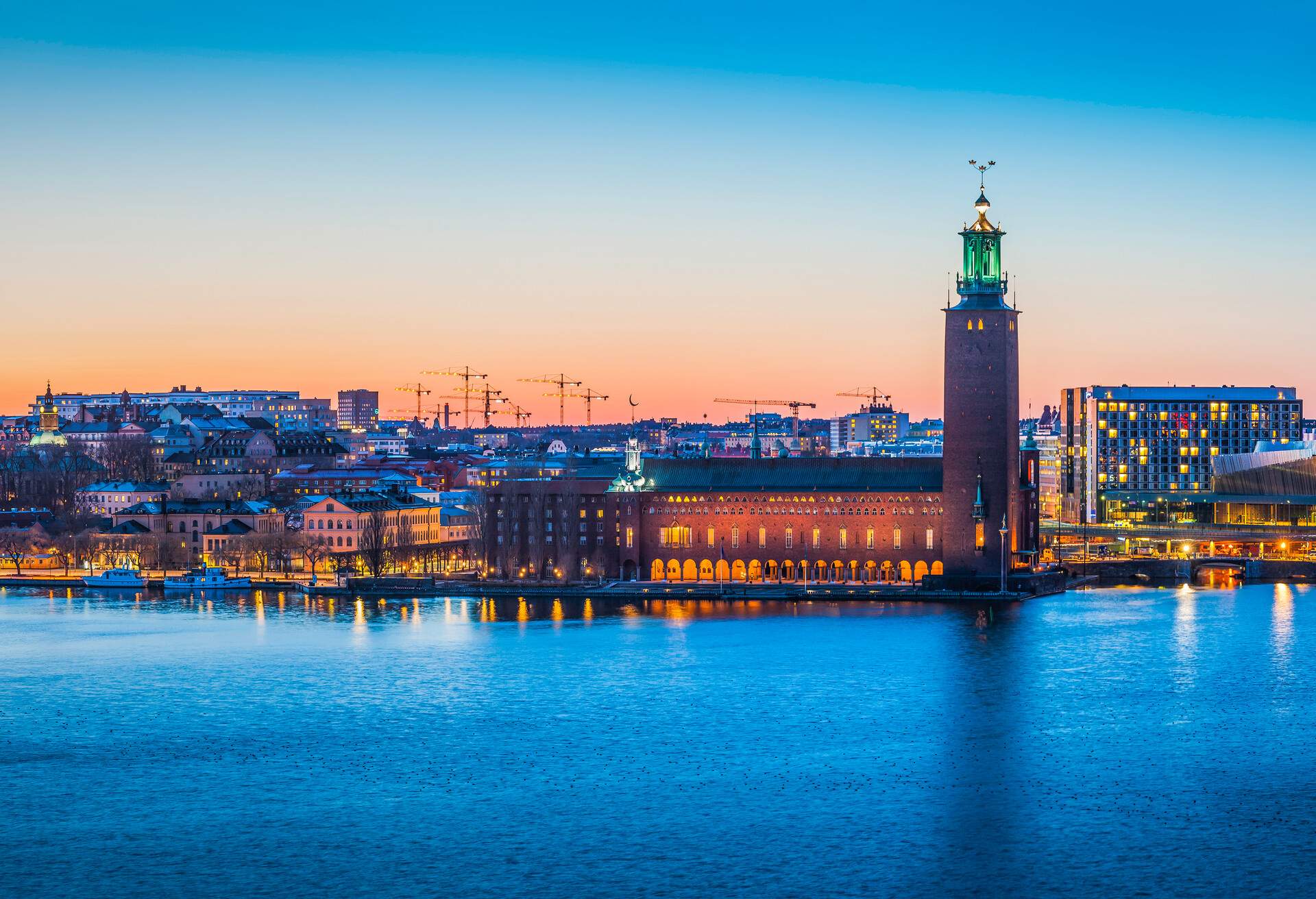 Warm glow of midsummer sunset over the historic tower of Stockholm City Hall, Stadshuset, spotlit at its iconic waterfront location on Kungsholmen island reflecting in the still waters of Riddarfjarden in the heart of Sweden's picturesque capital city. ProPhoto RGB profile for maximum color fidelity and gamut.