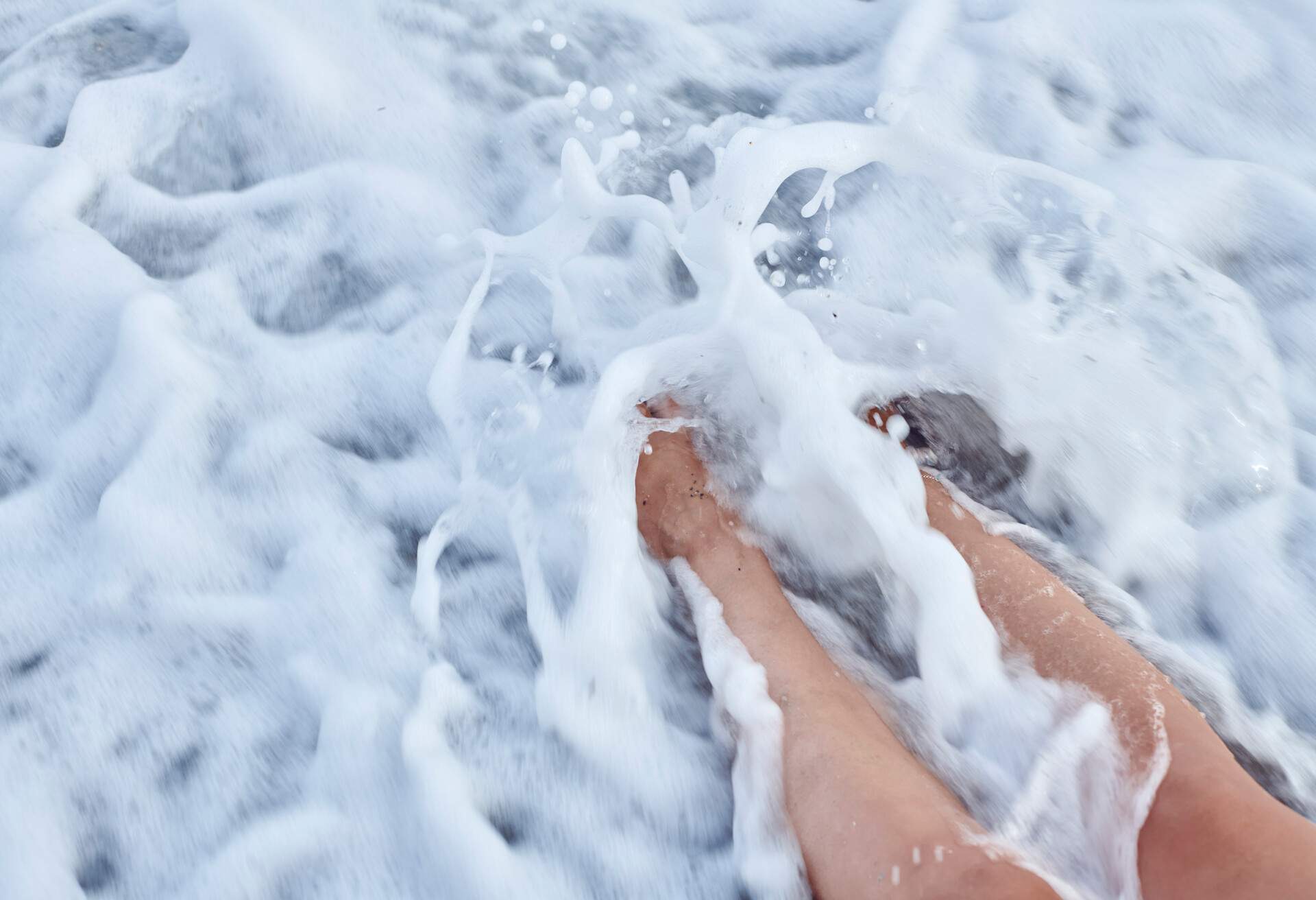 Close-up of a woman's feet with vitiligo on the sand on the beach in summertime