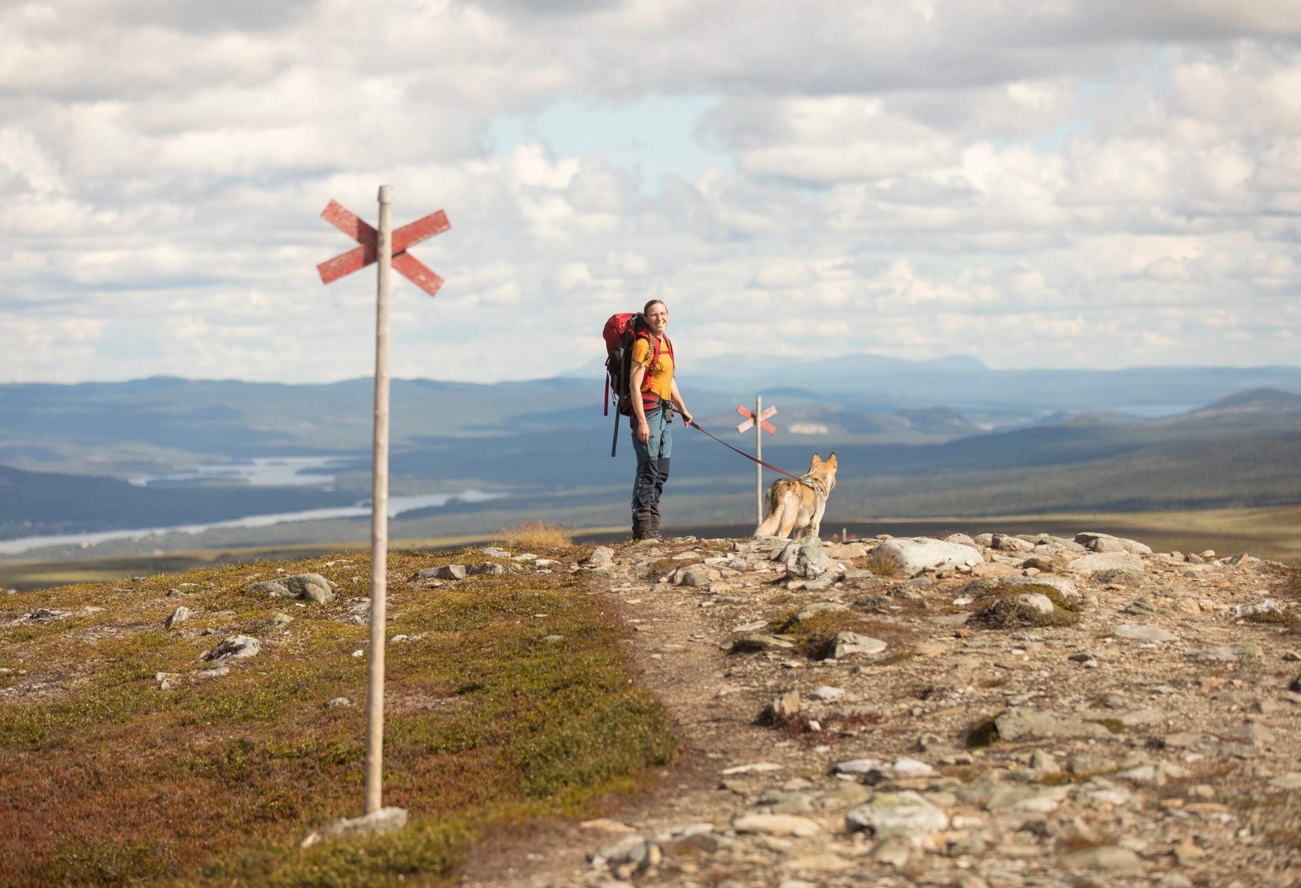 Woman wearing a backpack hiking with her dog on a mountain