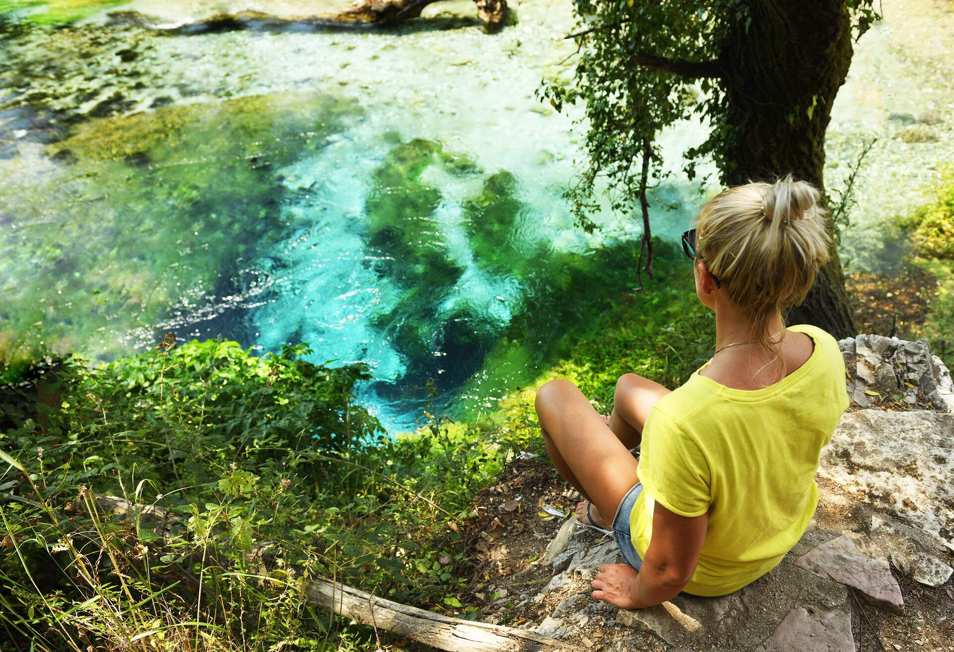 A girl of European appearance admires a beautiful source of turquoise color in the mountains of Albania.