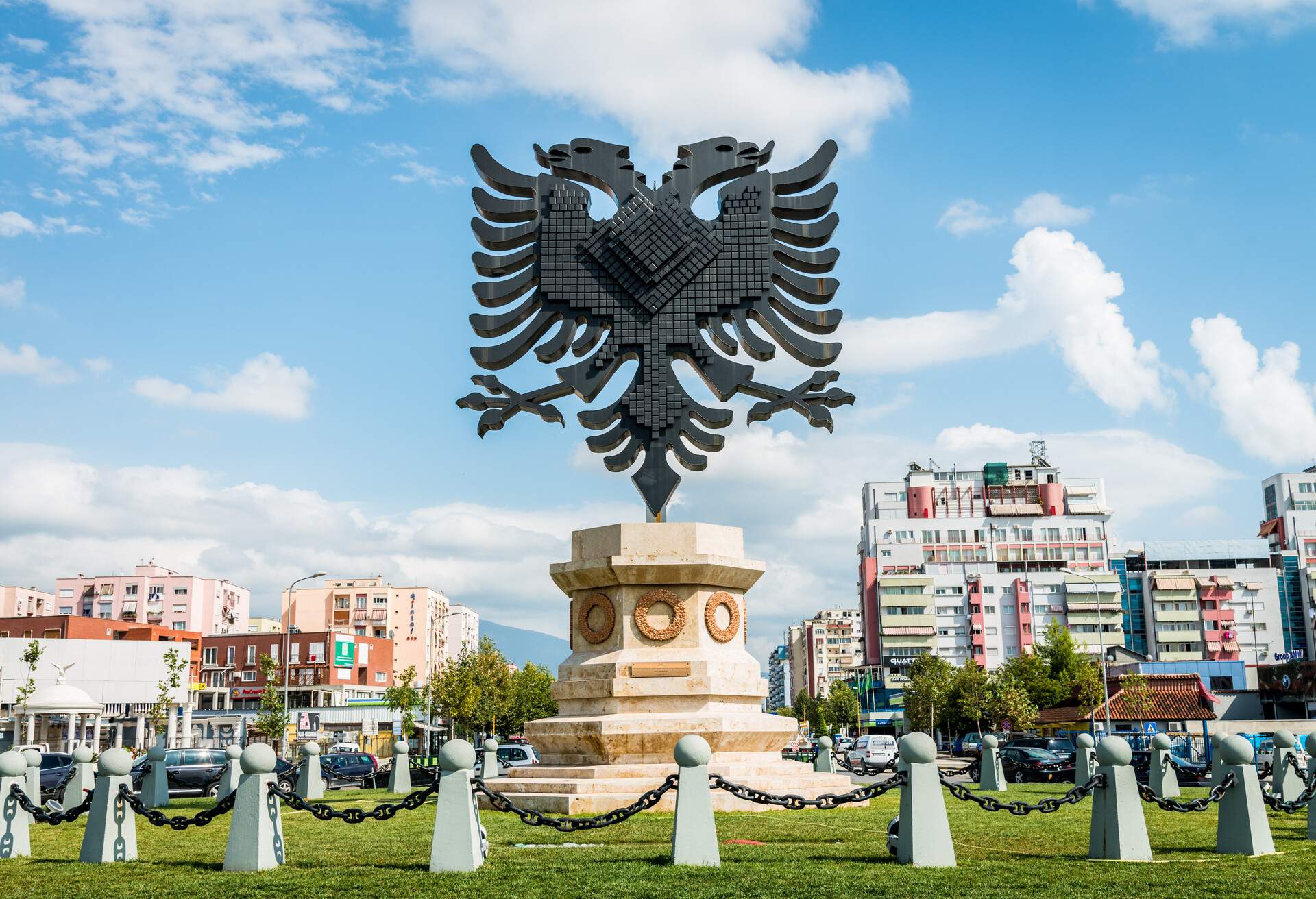 Giant Coat of Arms of Albania Emblem Statue in a street roundabout in the city center of Tirana under blue summer sky with fluffy cloudscape, Tirana, Capital of Albania, South Eastern Europe.