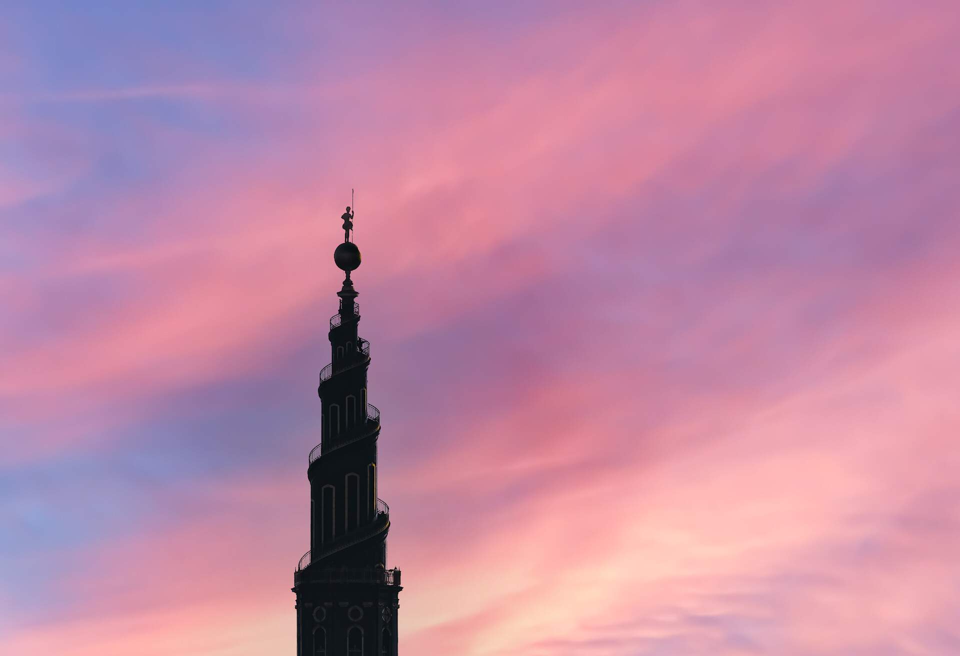 Large church spire silhouette on a colorful evening sky.