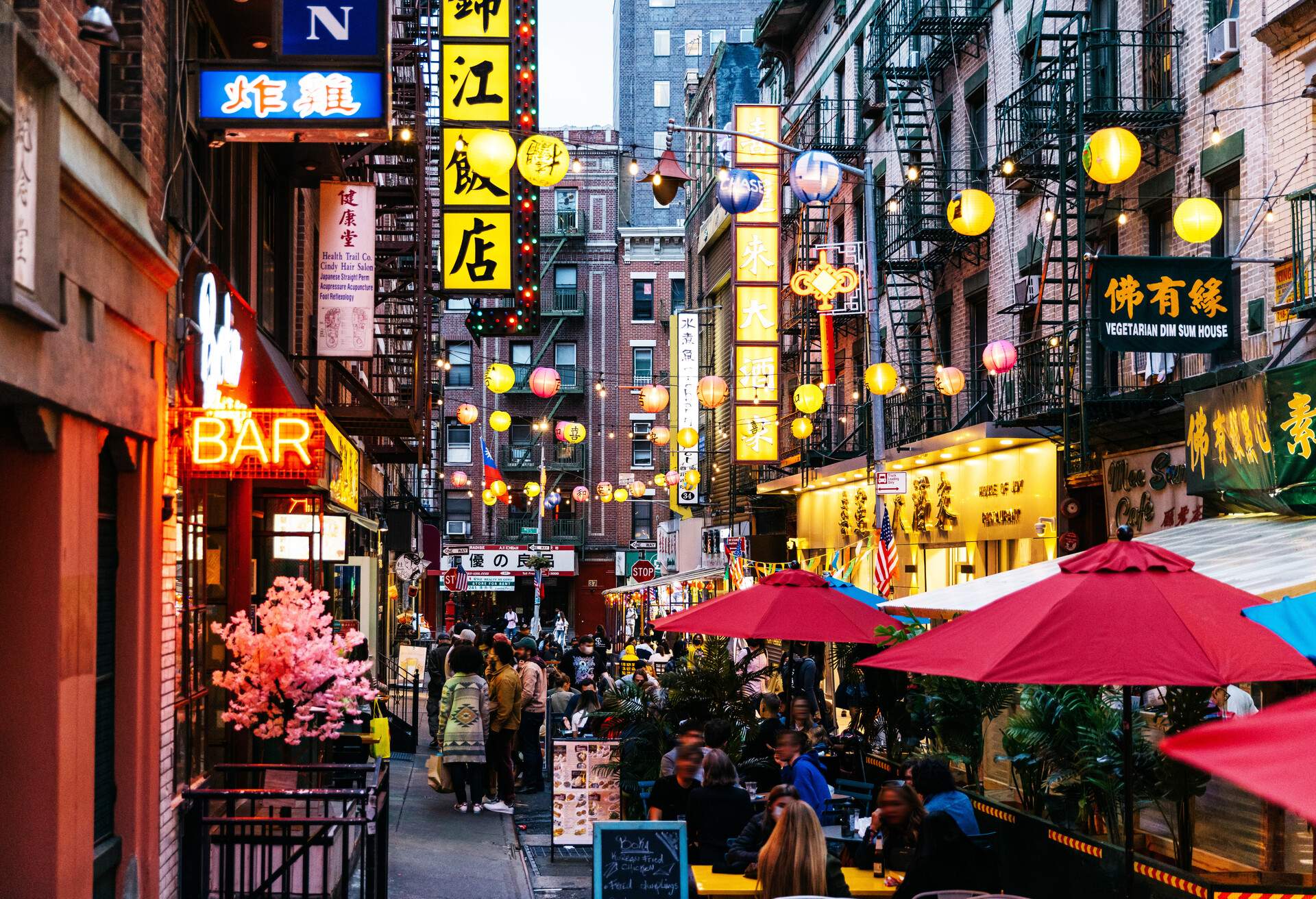 Customers like dining outdoors on the street illuminated by hanging lanterns between the old buildings.