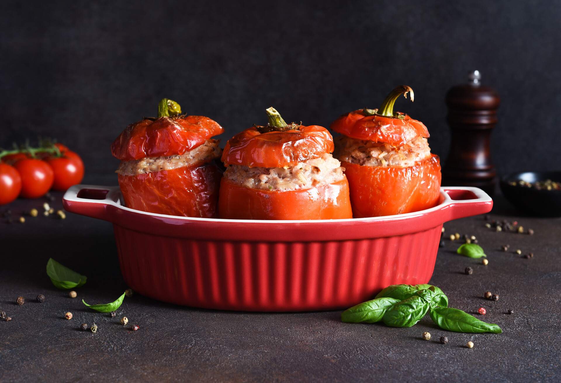 Stuffed pepper. Baked peppers with rice and meat and basil on a dark concrete background.