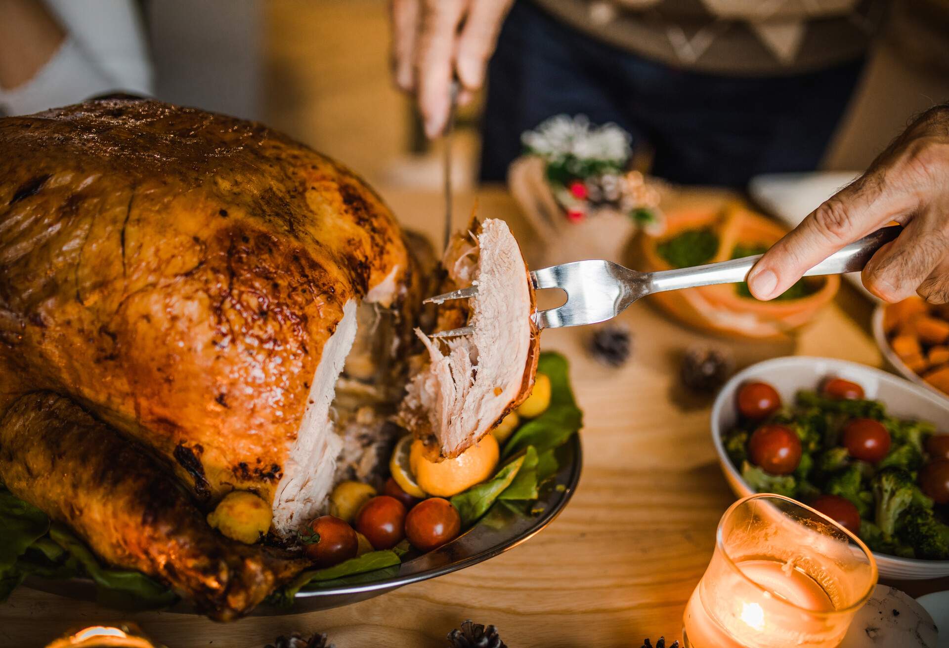 Close up of unrecognizable person carving white meat during dinner at dining table.