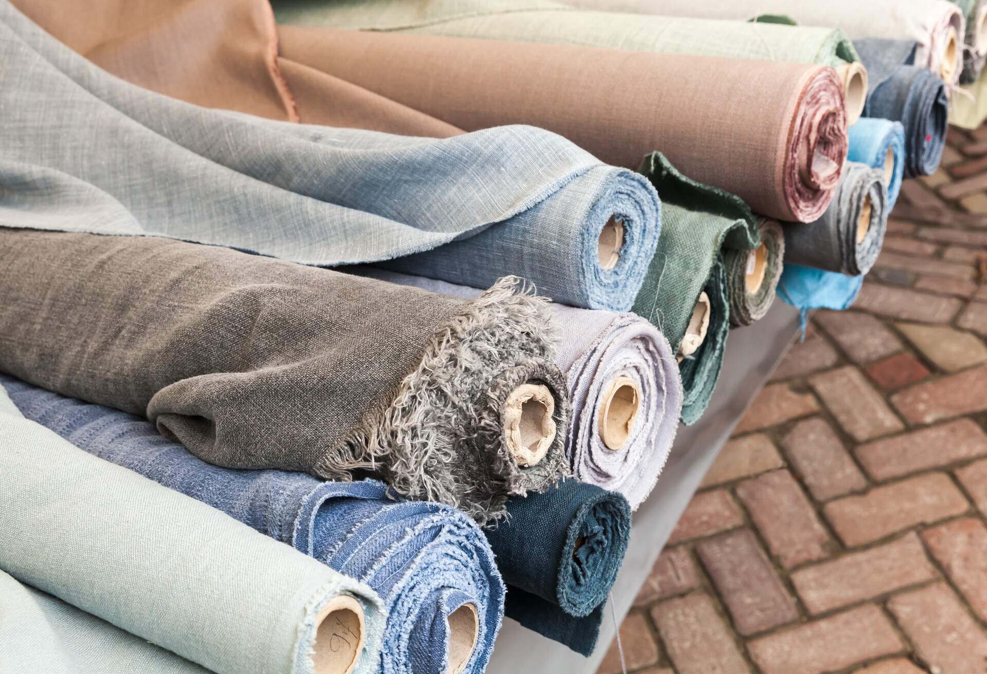 Rolls of natural linen cloth lie on the market counter in Amsterdam