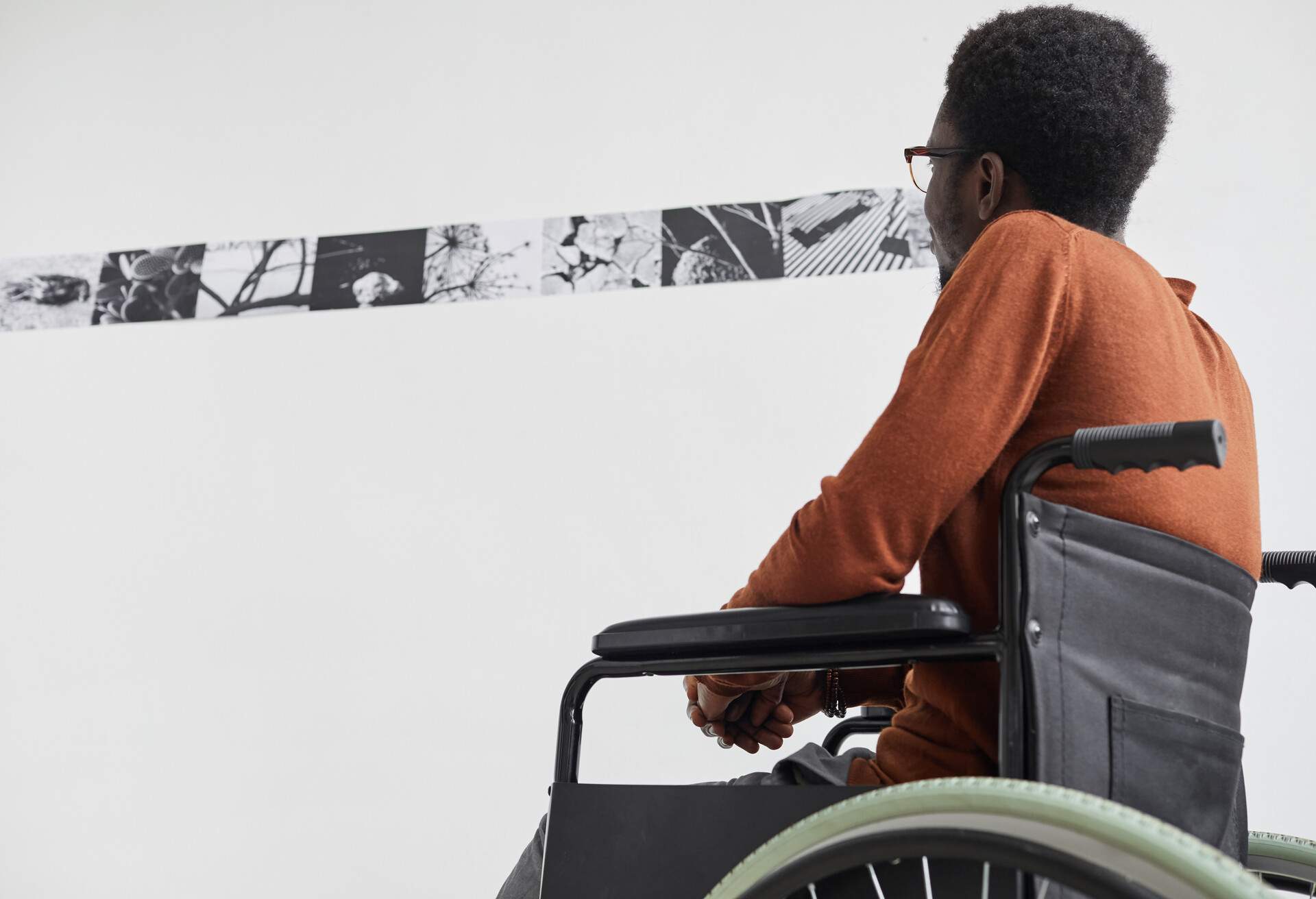 A man in a wheelchair looking at a black and white wall painting.