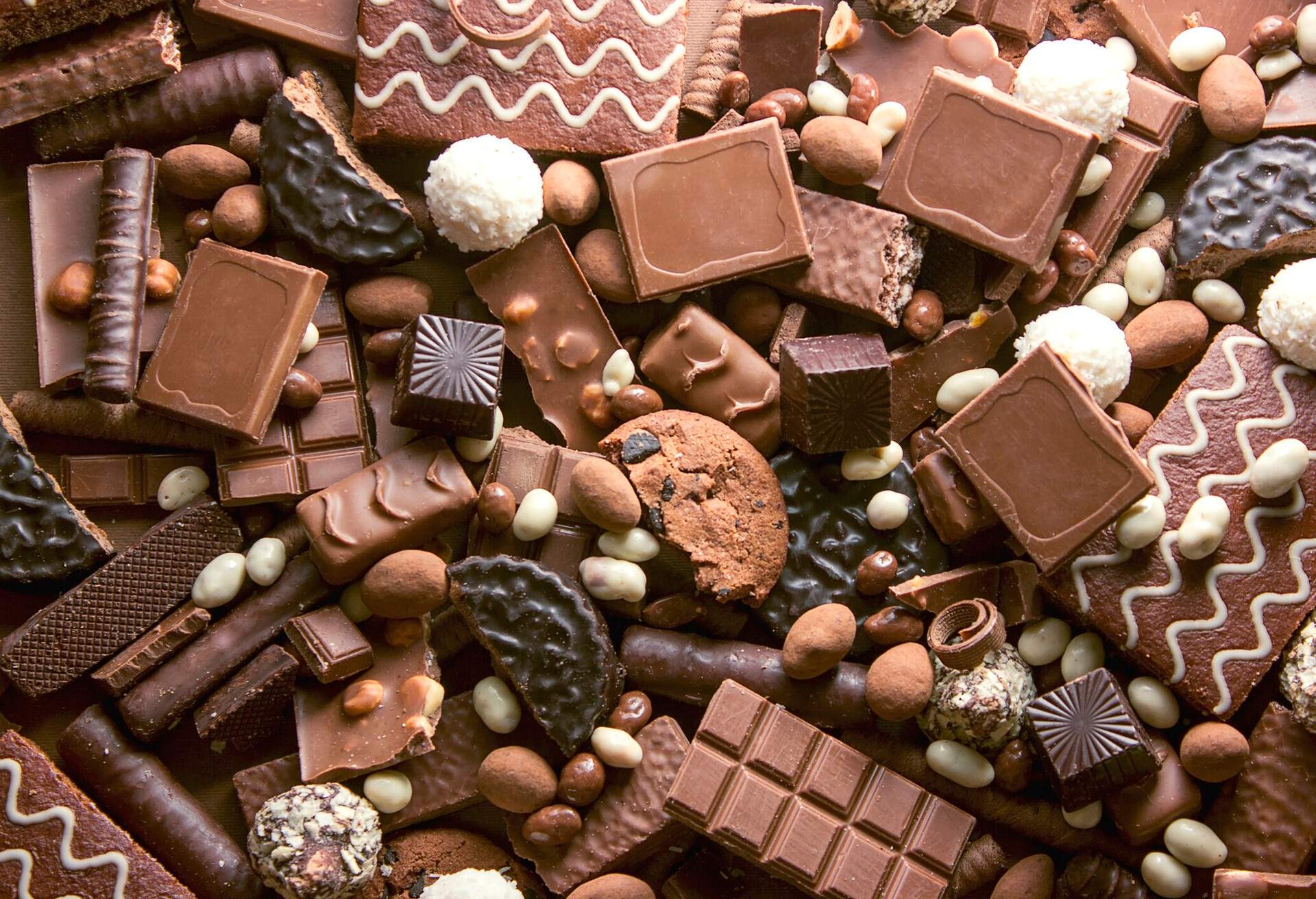 Chocolate background. Many pieces of chocolate, candies, cookies, biscuits, cakes and other sweets. Milk chocolate and dark chocolate. coconut candy
