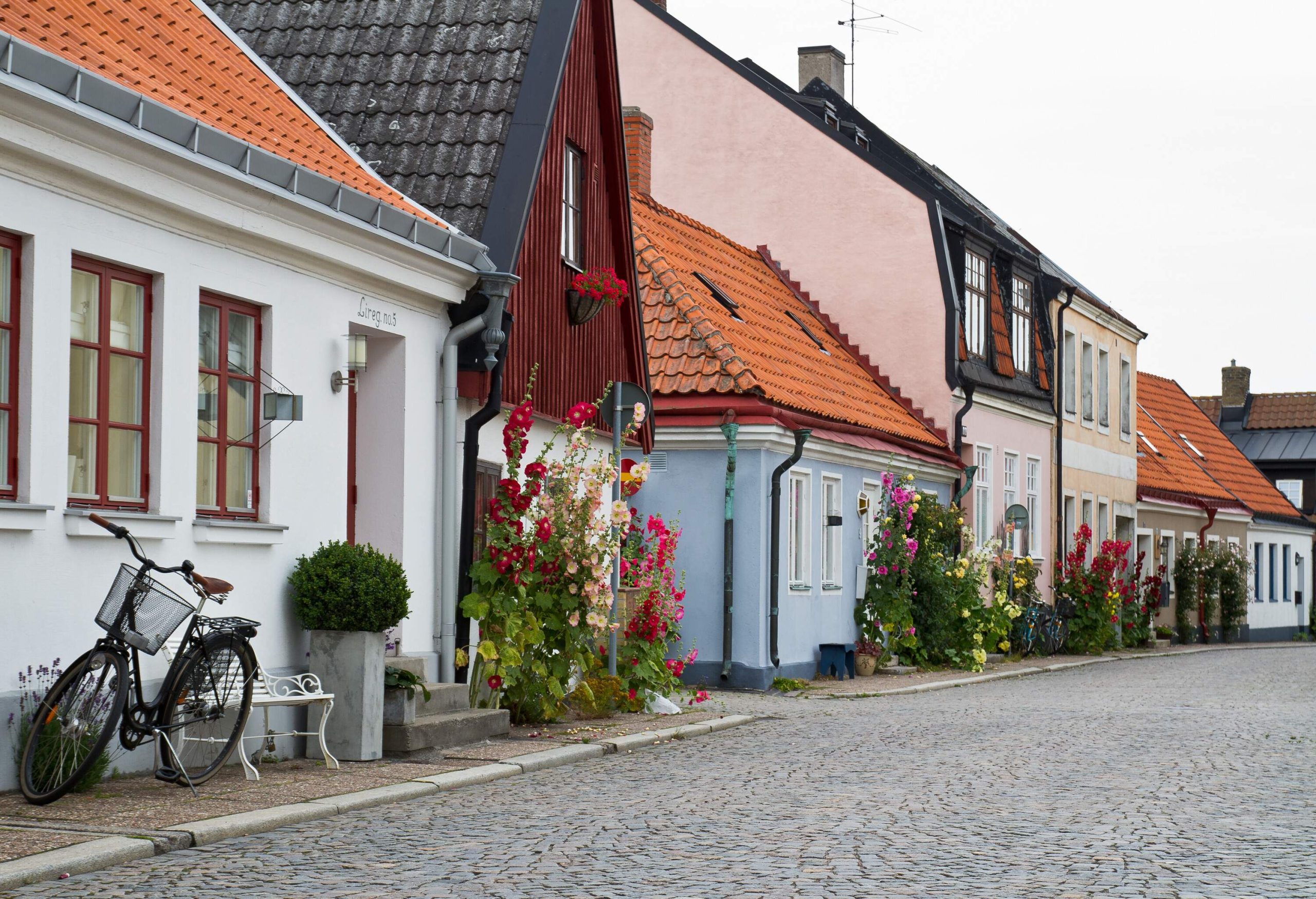 Colourful homes decked with flowers line a street with stone paving.