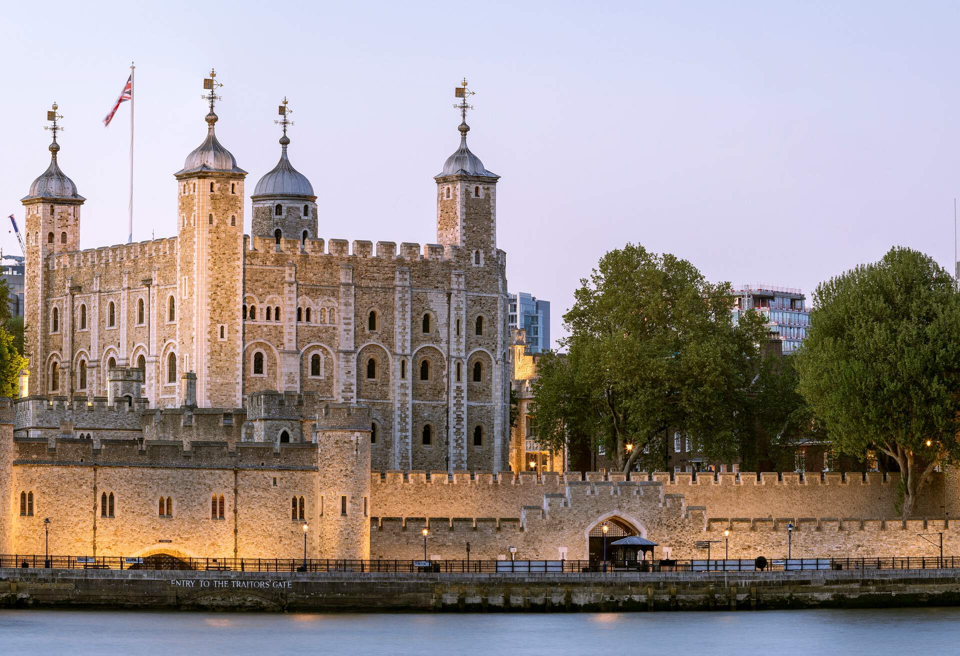 The Tower of London is an iconic castle with projecting four corner towers guarded by defensive walls on the river bank.
