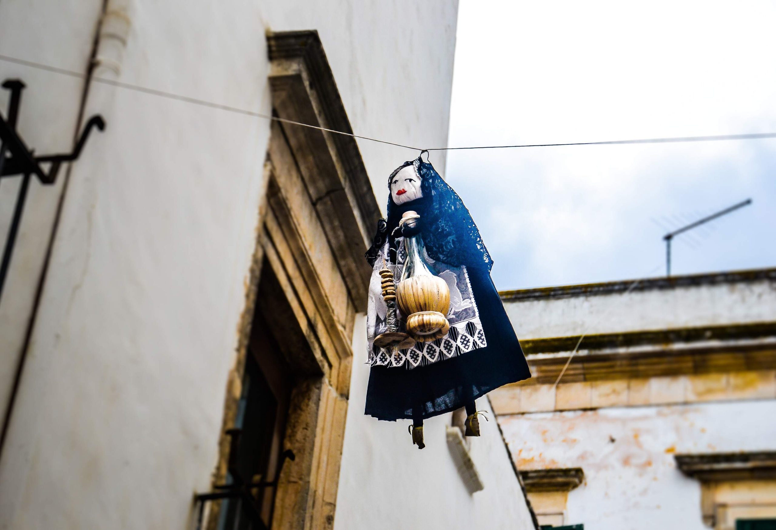 A traditional folk doll hangs in the middle of an old building.