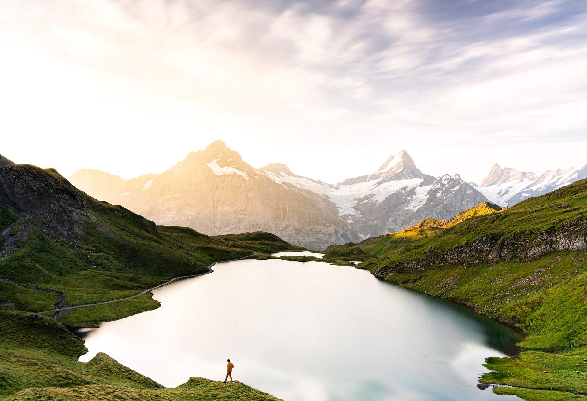 High angle view of hiker man walking at Bachalpsee lake during a misty sunrise, Grindelwald, Bernese Oberland, Bern Canton, Switzerland