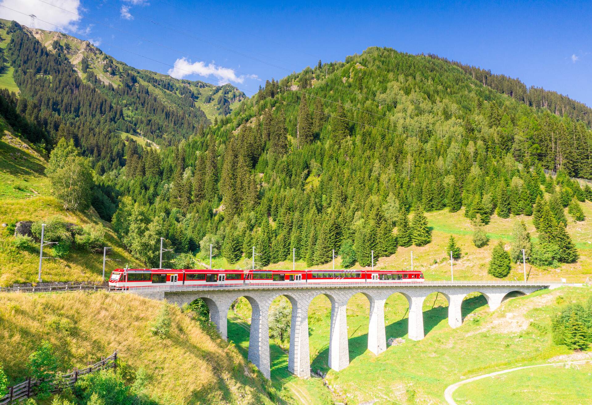 Summer sky on the Glacier Express train along Tujetsch viaduct surrounded by green woods in summer, Sedrun, Graubunden canton, Switzerland