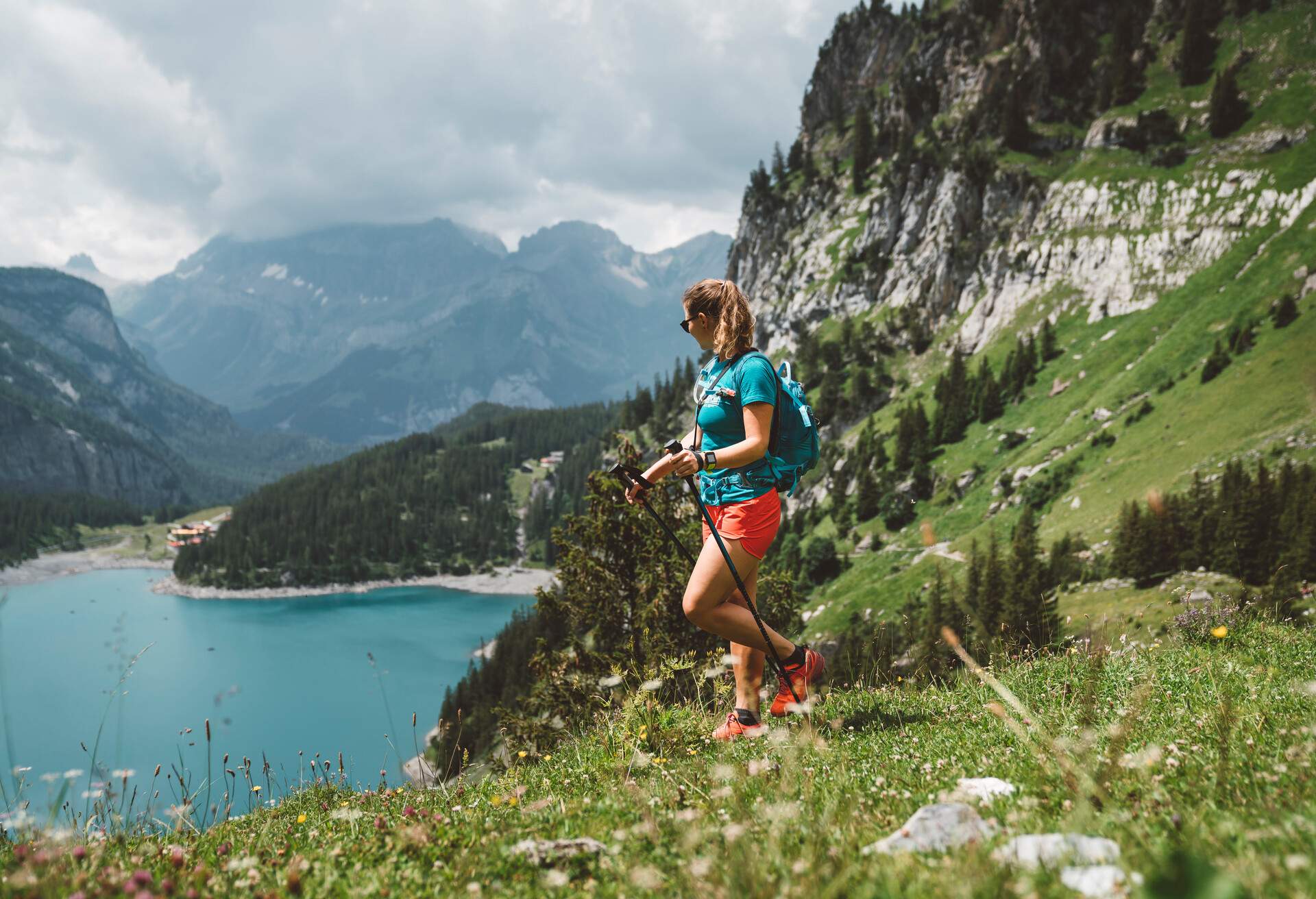 Woman hiking in the mountains by the Oeschinen lake in Berner Oberland region in central Switzerland. Hiker hiking in Swiss alps in the summer.