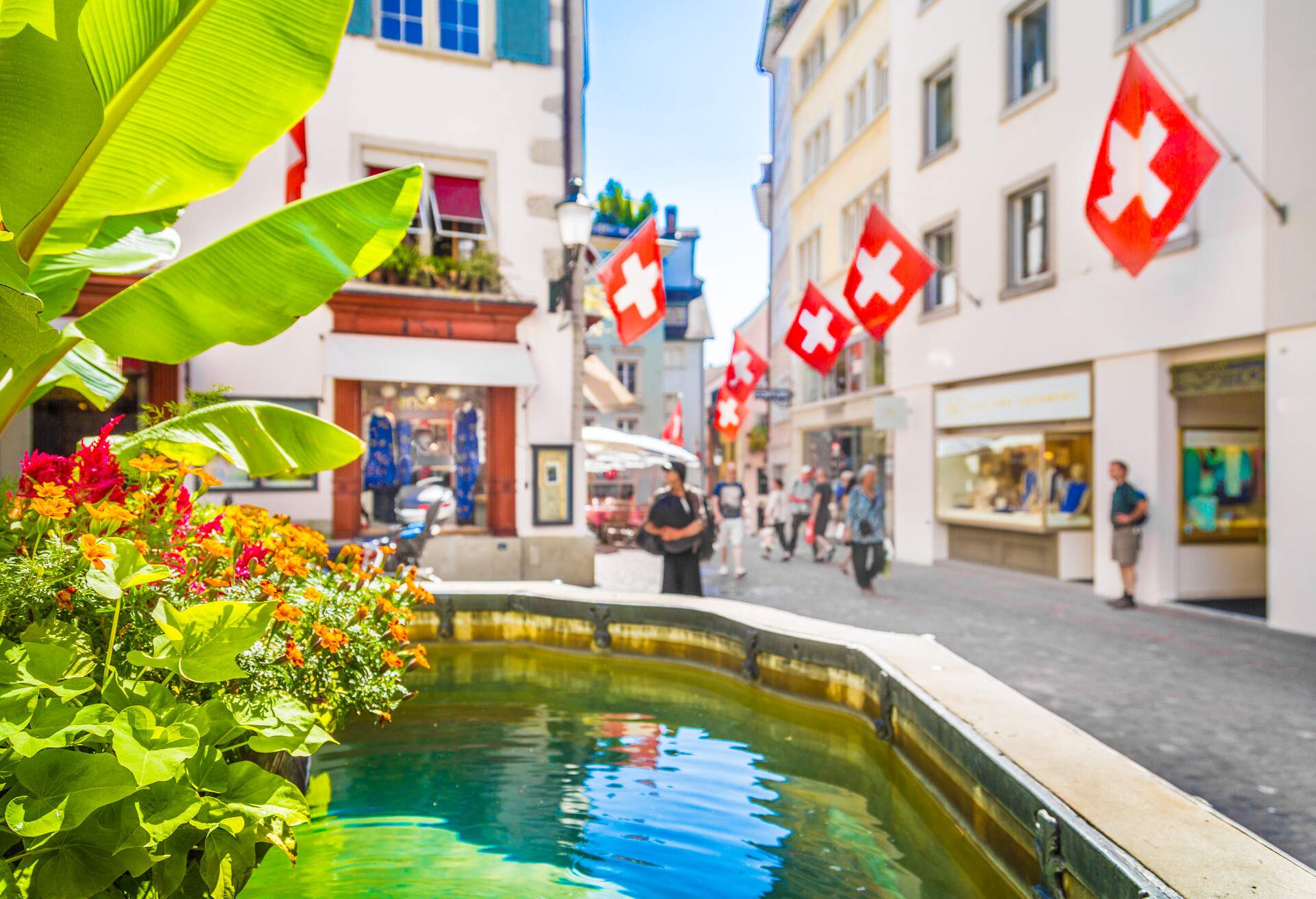 Historic city center of Zurich with Swiss flags hanging from buildings with bokeh background blur effect on a sunny day in summer, Switzerland.