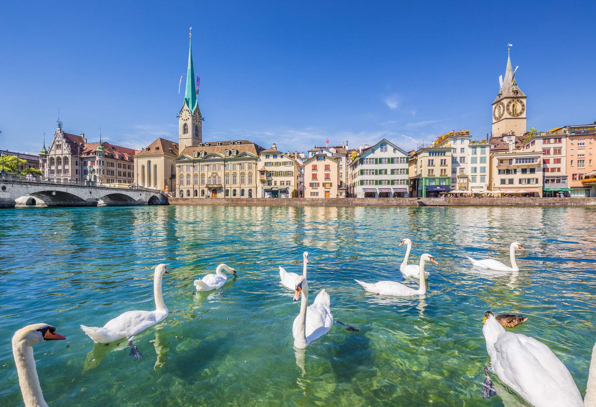 Beautiful view of the historic city center of Zurich with famous Fraumunster and Sankt Peter Church and swans on river Limmat on a sunny day with blue sky in summer, Canton of Zurich, Switzerland; Shutterstock ID 415059445; Purpose: Destiny; Brand (KAYAK, Momondo, Any): Any