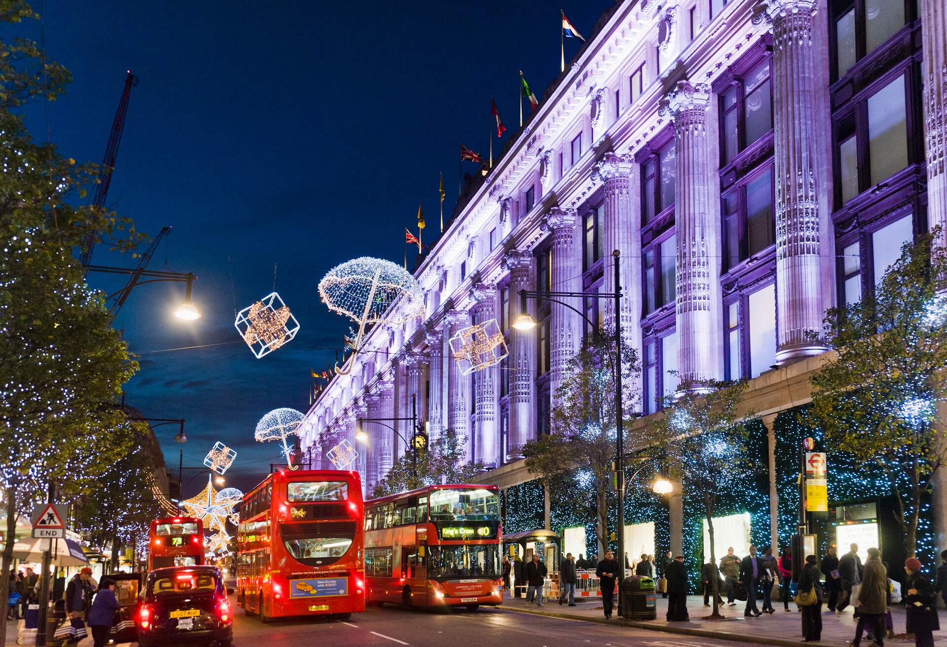 Oxford Street is bustling with lighted Christmas decorations, red double-decker buses and black taxis as people ply the streets.