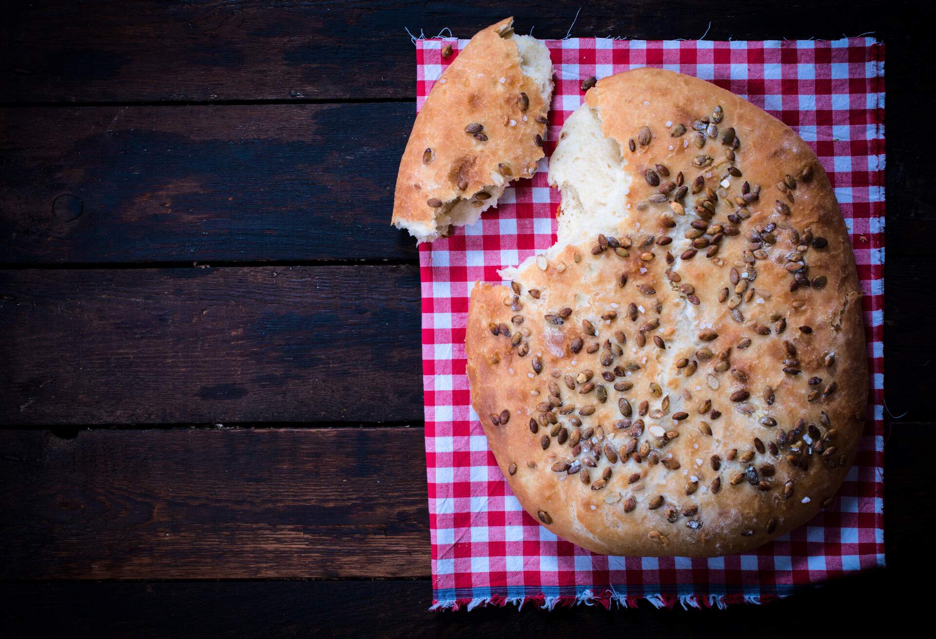 Baked homemade bannock bread with seeds on wooden background with blank space
