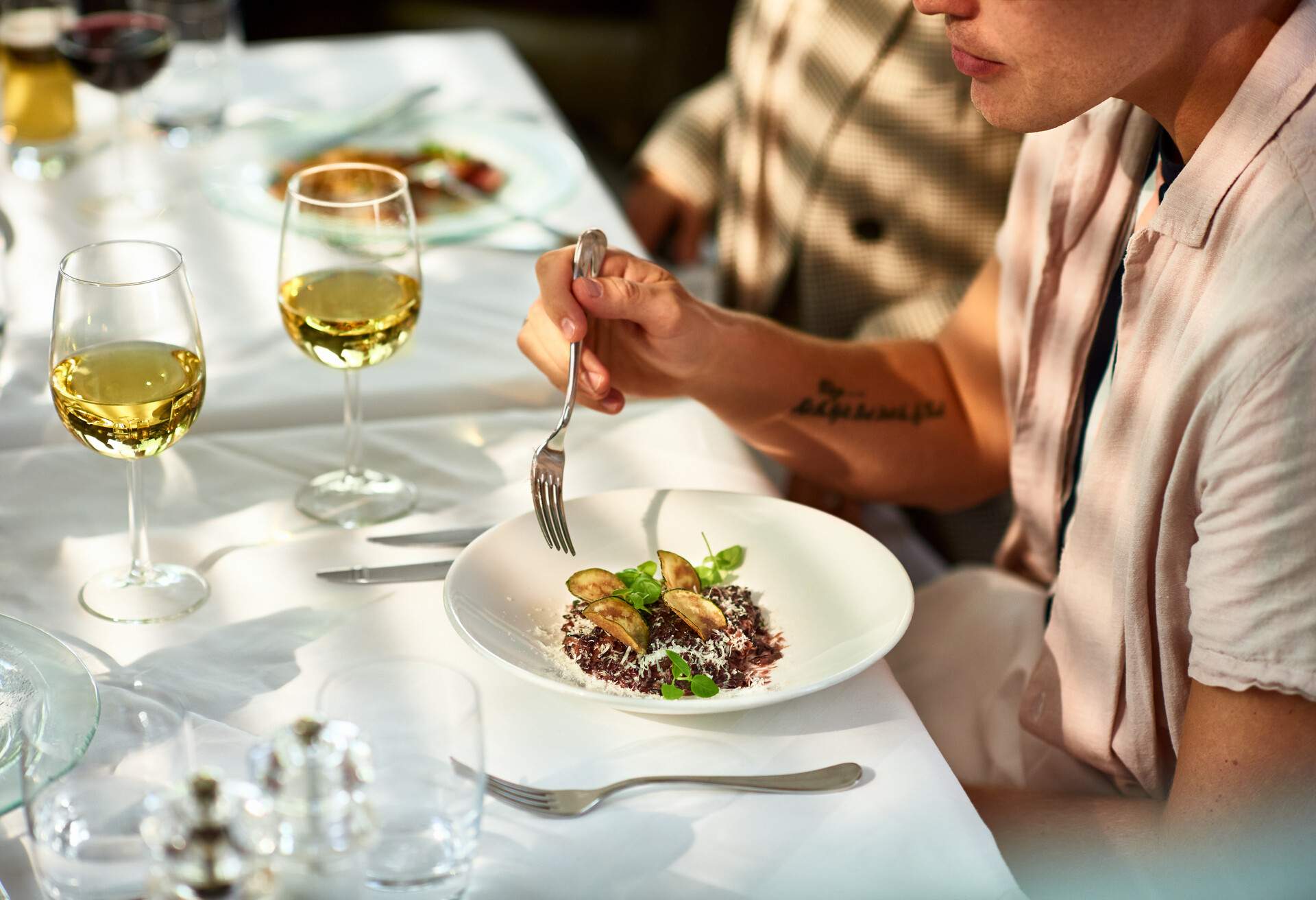 Young man sitting at table with starter and white wine 