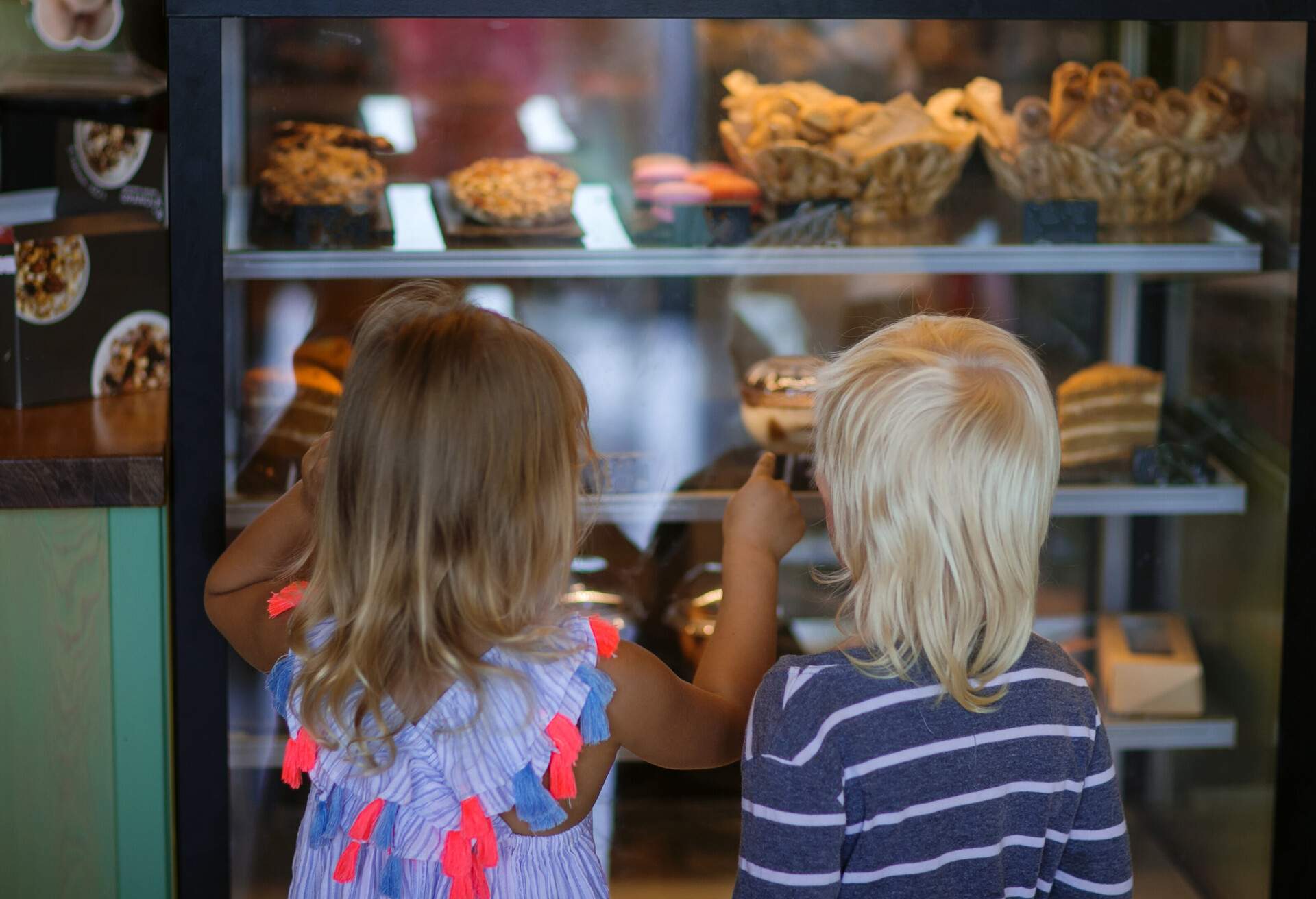 boy and girl in a cafe in front of a shop window are choosing a dessert