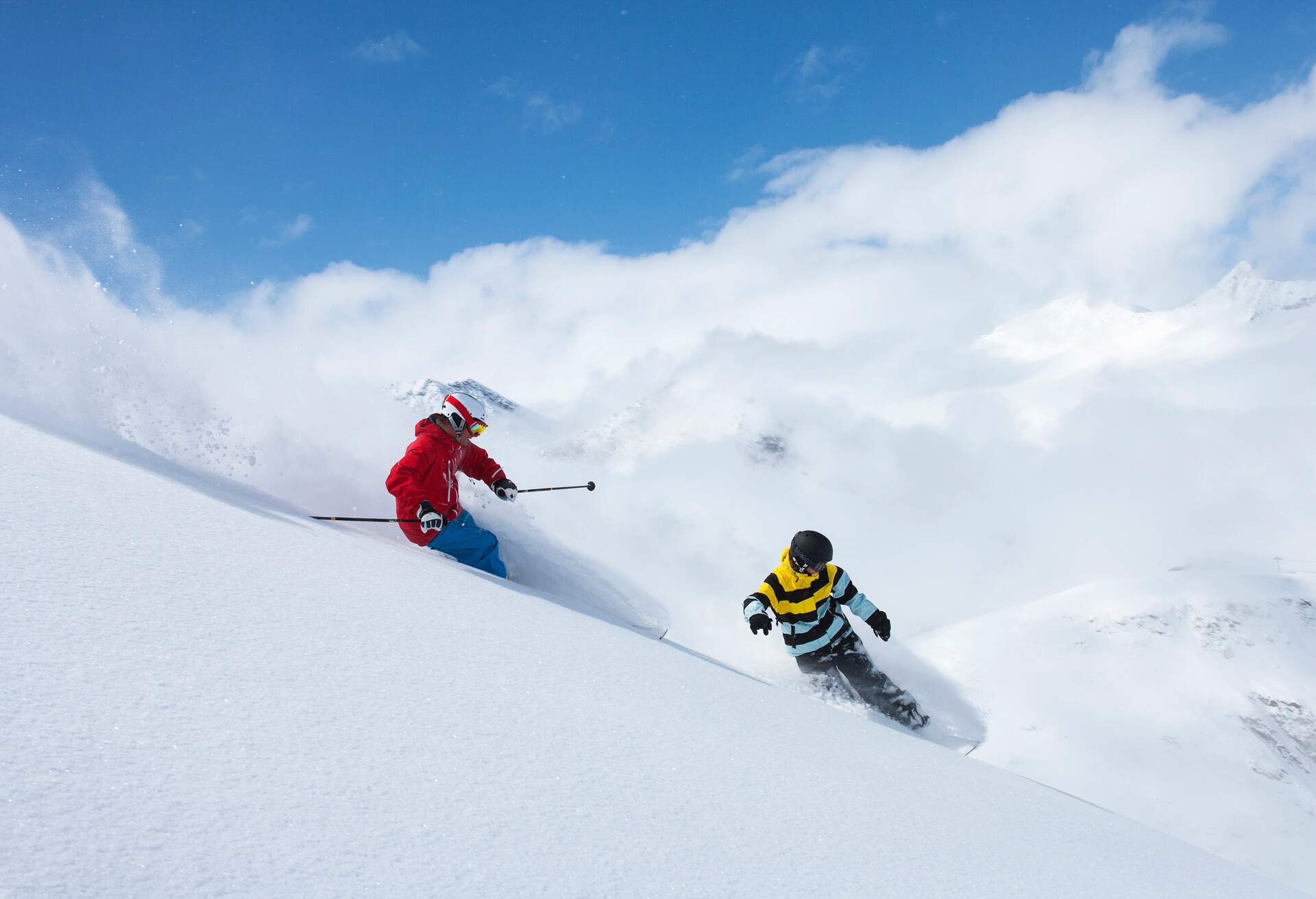 Two skiers side slipping on a snow hill.