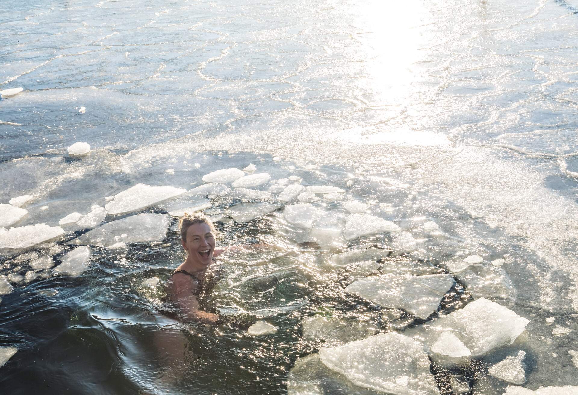 A happy woman treading in an icy ocean.