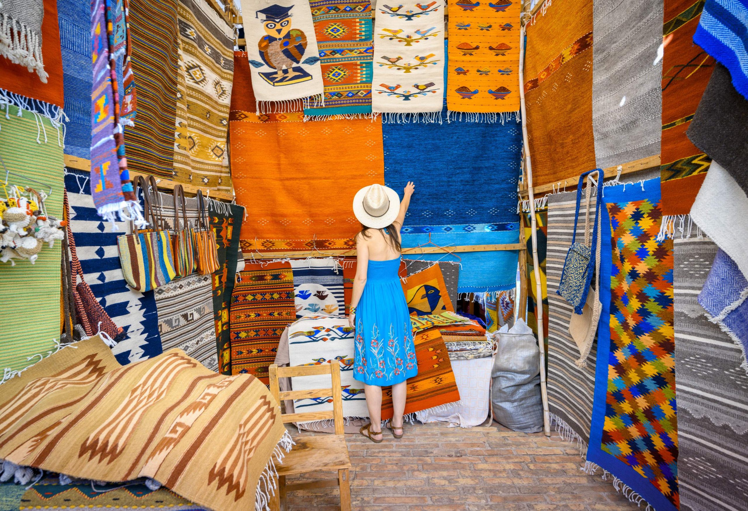 dest_mexico_oaxaca_theme_people_woman_shopping_local-rugs_gettyimages-1209650668_universal_within-usage-period_99221