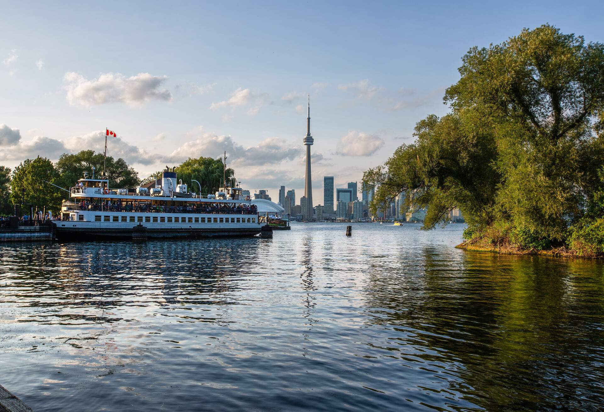 The Toronto city skyline at dusk as seen from the viewpoint of the Toronto Islands.  A municipal ferry shuttles passengers from the Toronto Islands to the mainland.