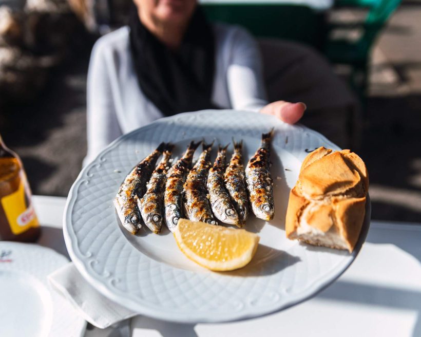SPAIN_MALAGA_WOMAN_HOLDING_PLATE_FRESHLY_COOCKED_GRILLED_SARDINES