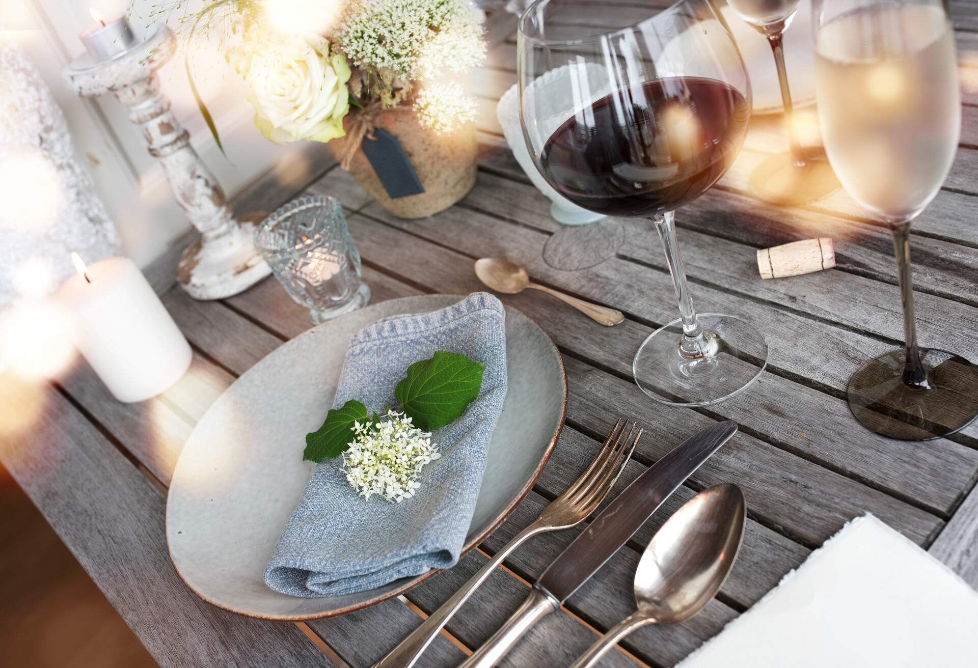 Decoration on a rustic wooden table for a romantic dinner with wine and golden bokeh 